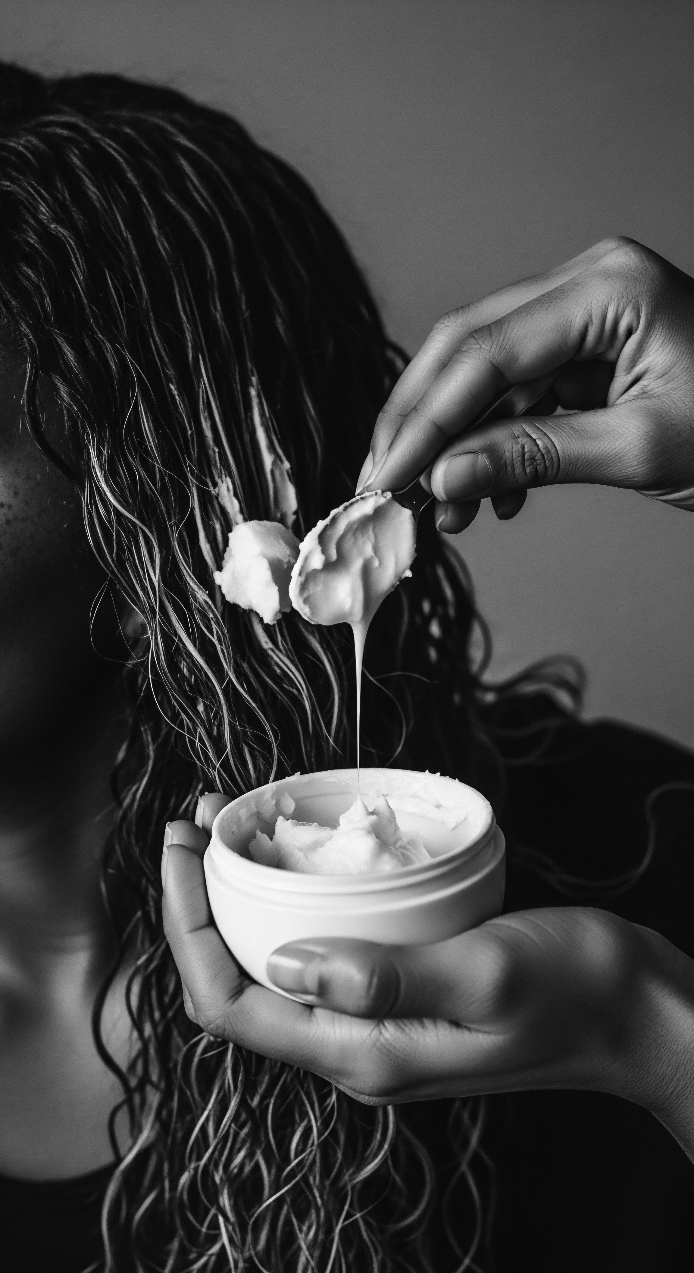 Applying Rich Hair Mask to Intensely Coiled Textured Hair at Home The intimate portrait celebrates ancestral heritage through intentional hair care, a woman lovingly coats her intensely coiled textured hair with a nourishing hair mask. A self-care ritual honoring the legacy of Black hair traditions, showcasing the commitment to healthy, expressive styling with holistic products.