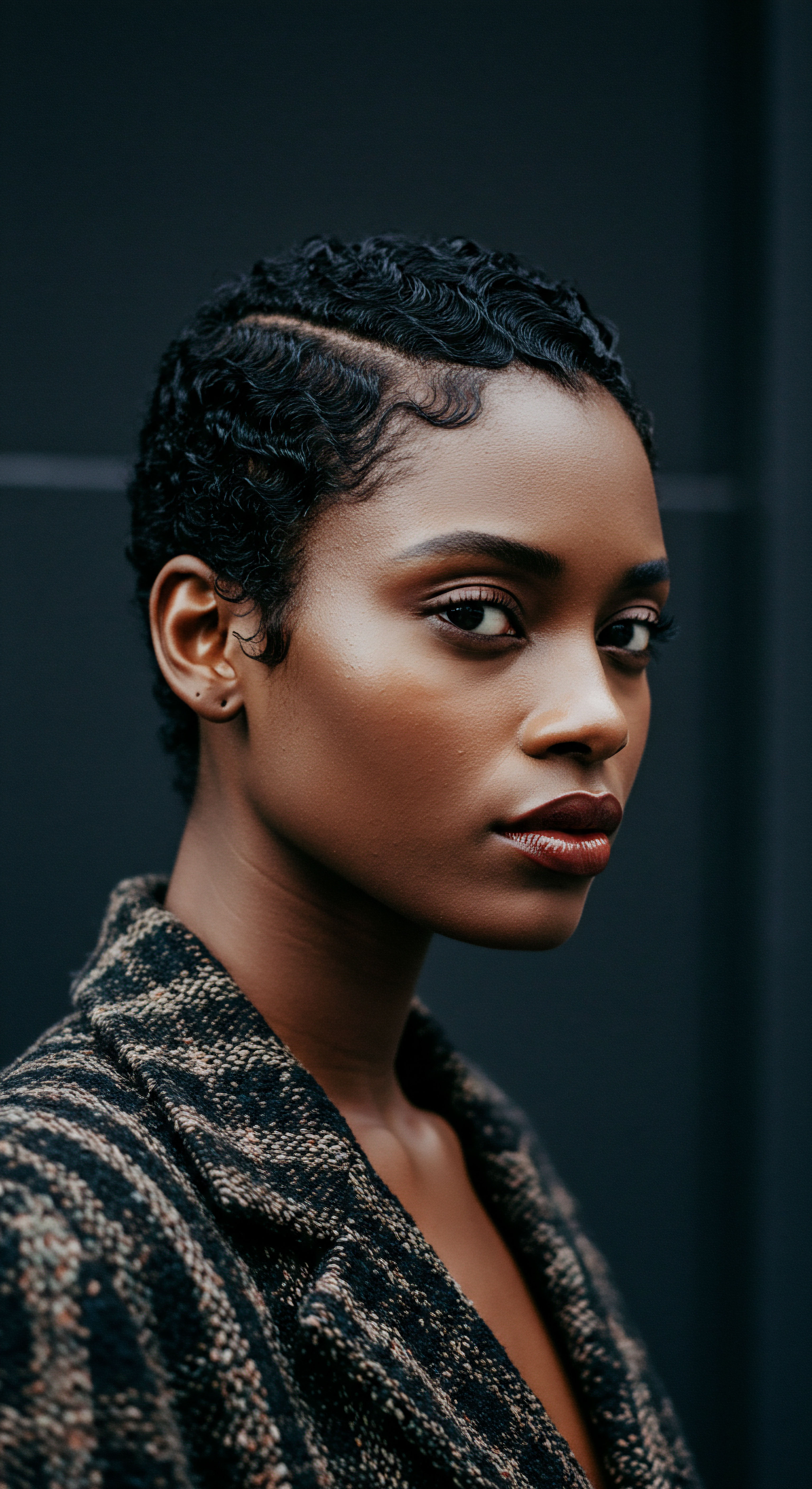 Artful Coily Hair Pattern Defining Heritage And Styling Care This compelling portrait exemplifies intentional textured hair care and styling mastery. The meticulously set deep coily patterns and intricate finger waves demonstrate superb definition, moisture retention, and hair elasticity. It's a vibrant ode to Black hair heritage, promoting scalp health and resilient hair fibers through timeless aesthetic choices.