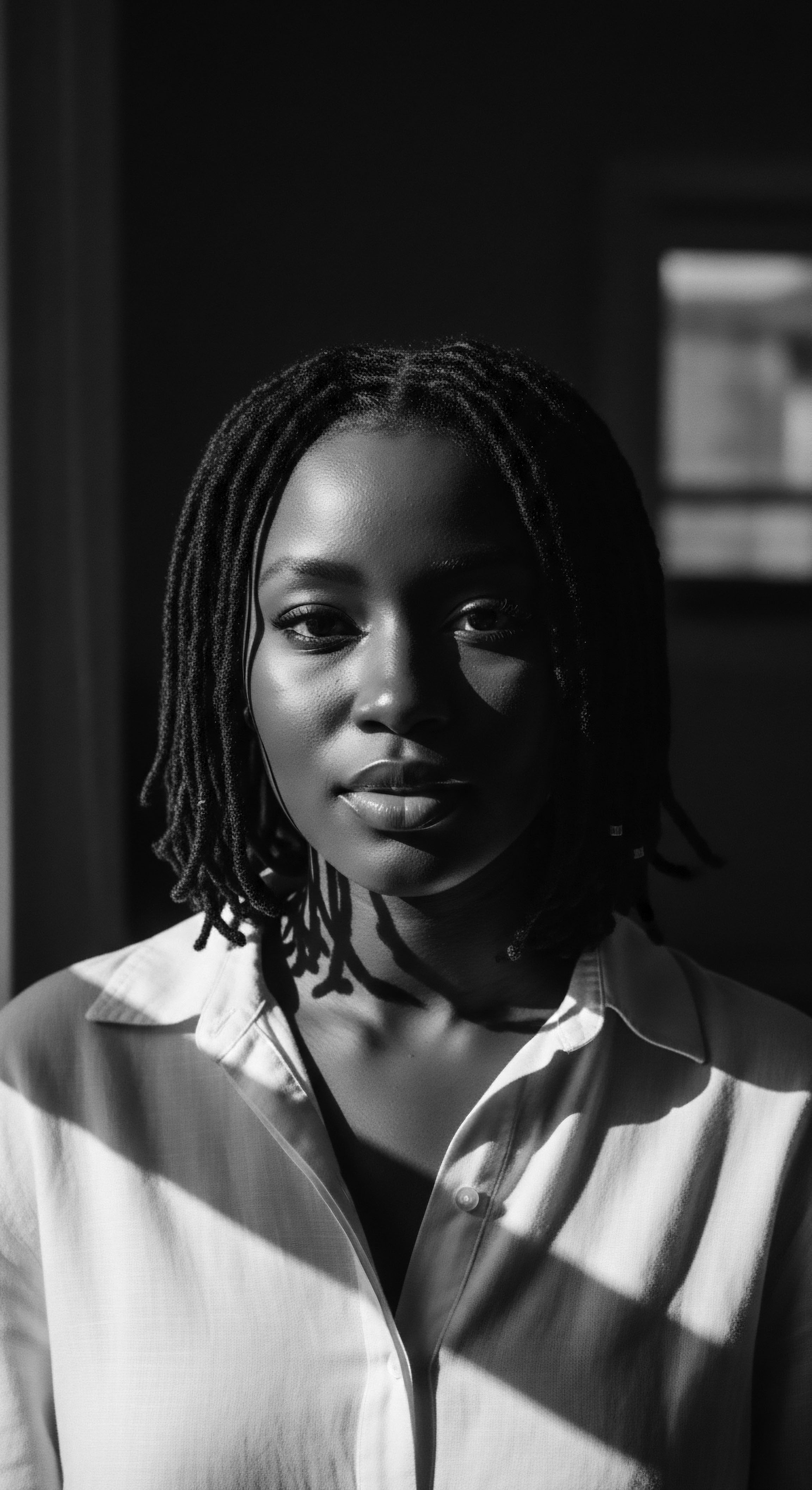 Black and White Portrait Radiant Woman with Dreads Sunlight and Shadow The evocative black and white portrait emphasizes light and shadow on the woman's face and locs, underscoring her strength and resilience. It beautifully captures the essence of beauty amplified by the texture and form of her naturally styled hair, rooted in heritage and self-expression.