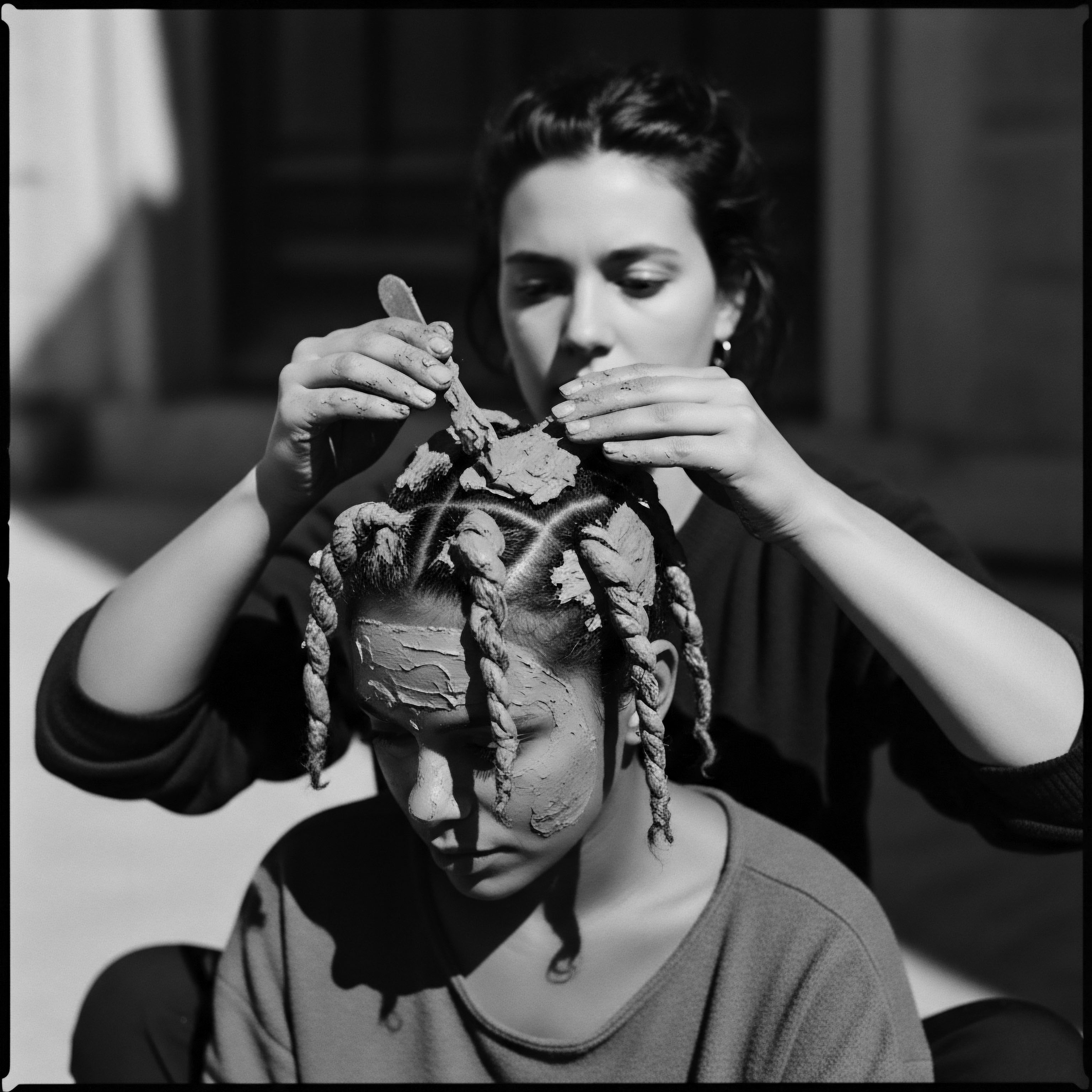 Clay Mask Applied to Braided Textured Hair: A Heritage Ritual The application of clay to textured hair braids evokes ancestral traditions, symbolizing a connection to heritage and holistic hair wellness practices. This intimate moment emphasizes the care invested in maintaining strong, culturally significant hair formations and scalp health with natural ingredients.