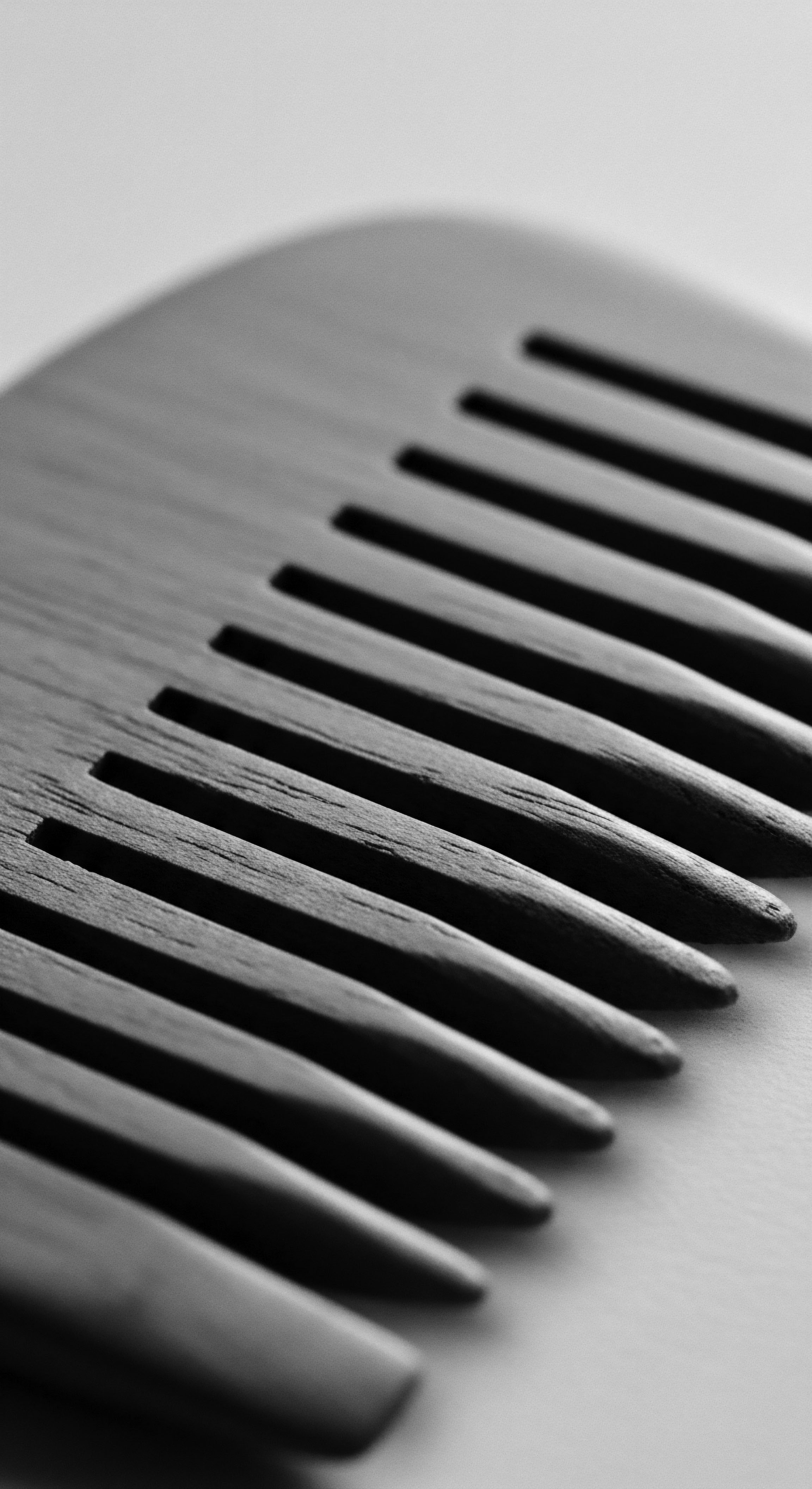 Close Up Black and White Image of a Wooden Hair Comb This finely crafted wooden comb, captured in black and white, embodies ancestral wisdom and mindful practices in textured hair care. A celebration of natural beauty through sustainable tools, reflecting cultural commitment to holistic wellness and enhancing spiral hair formations with intention.