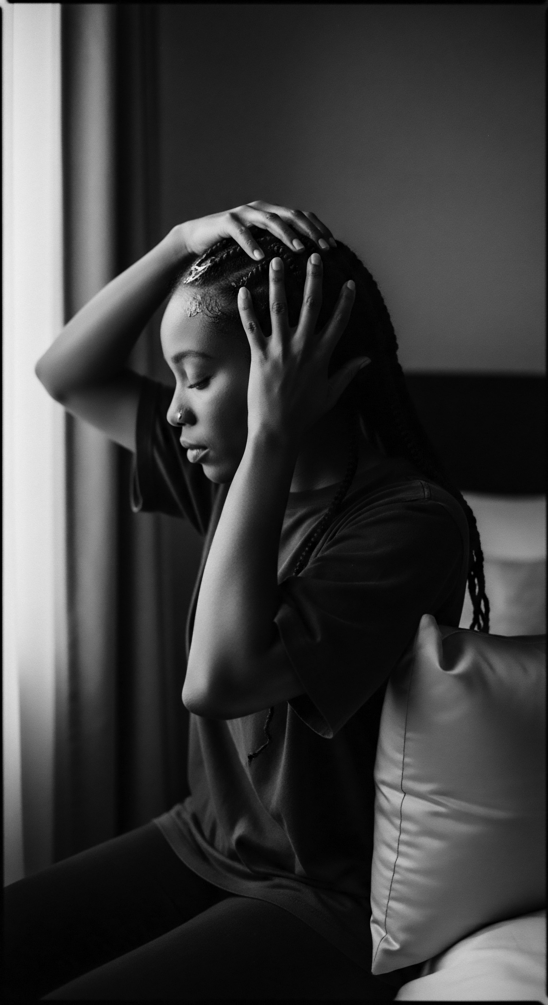 Contemplative Portrait of Black Woman with Braided Hair Near Window Bathed in gentle light, this thoughtful portrait embodies quiet strength, showcasing elegant box braids. The moment of self-reflection underscores ancestral connections intertwined with contemporary self-expression through textured hair formation, enhanced by her personal style, celebrating Black womanhood.