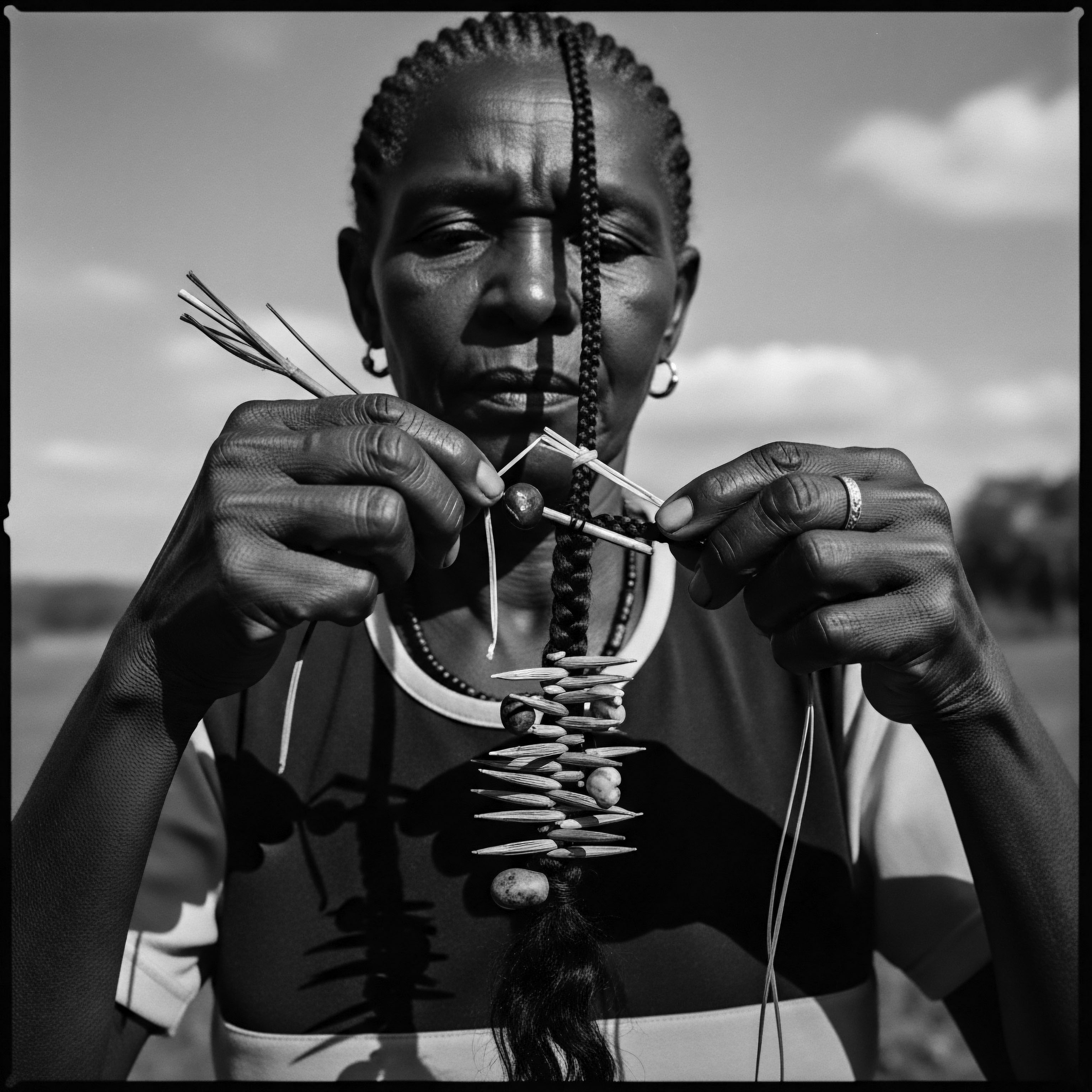 Elderly Woman Weaving Tradition Textured Hair Ancestral Craft Black and White This image embodies the fusion of ancestral heritage and present-day artistry, as an elder skillfully weaves a hair adornment onto textured hair, reflecting holistic well-being and cultural pride through the careful selection of natural materials and practiced techniques passed down through generations.