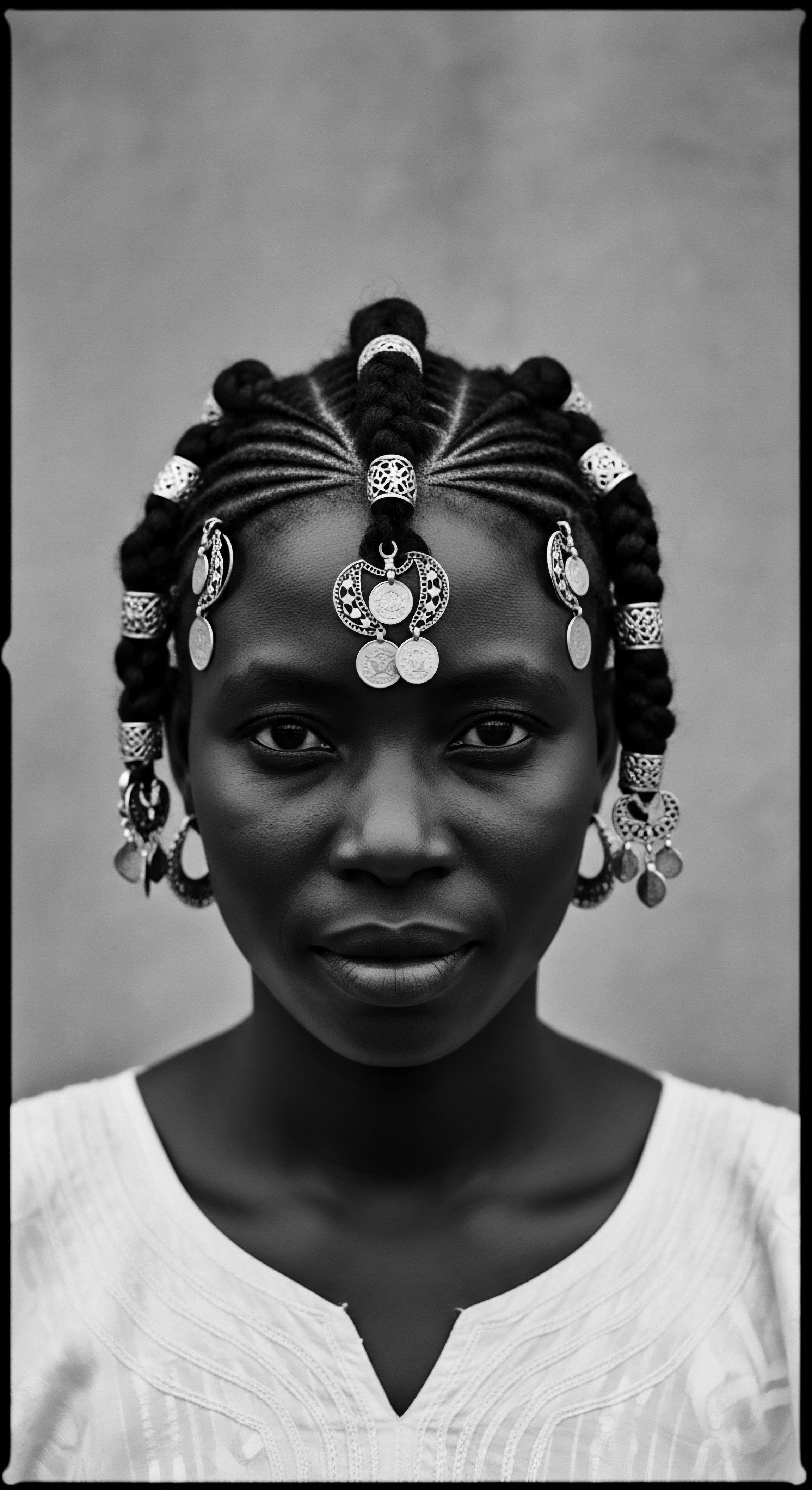 Elegant Black Woman with Braided Hairstyle and Silver Coin Adornments This poised portrait encapsulates the beauty of Black hair traditions, showcasing elaborate braiding artistry enhanced by striking silver adornments. The image celebrates heritage, identity, and individual expression through an elegant display of textured hair formation, promoting cultural appreciation and visual storytelling.