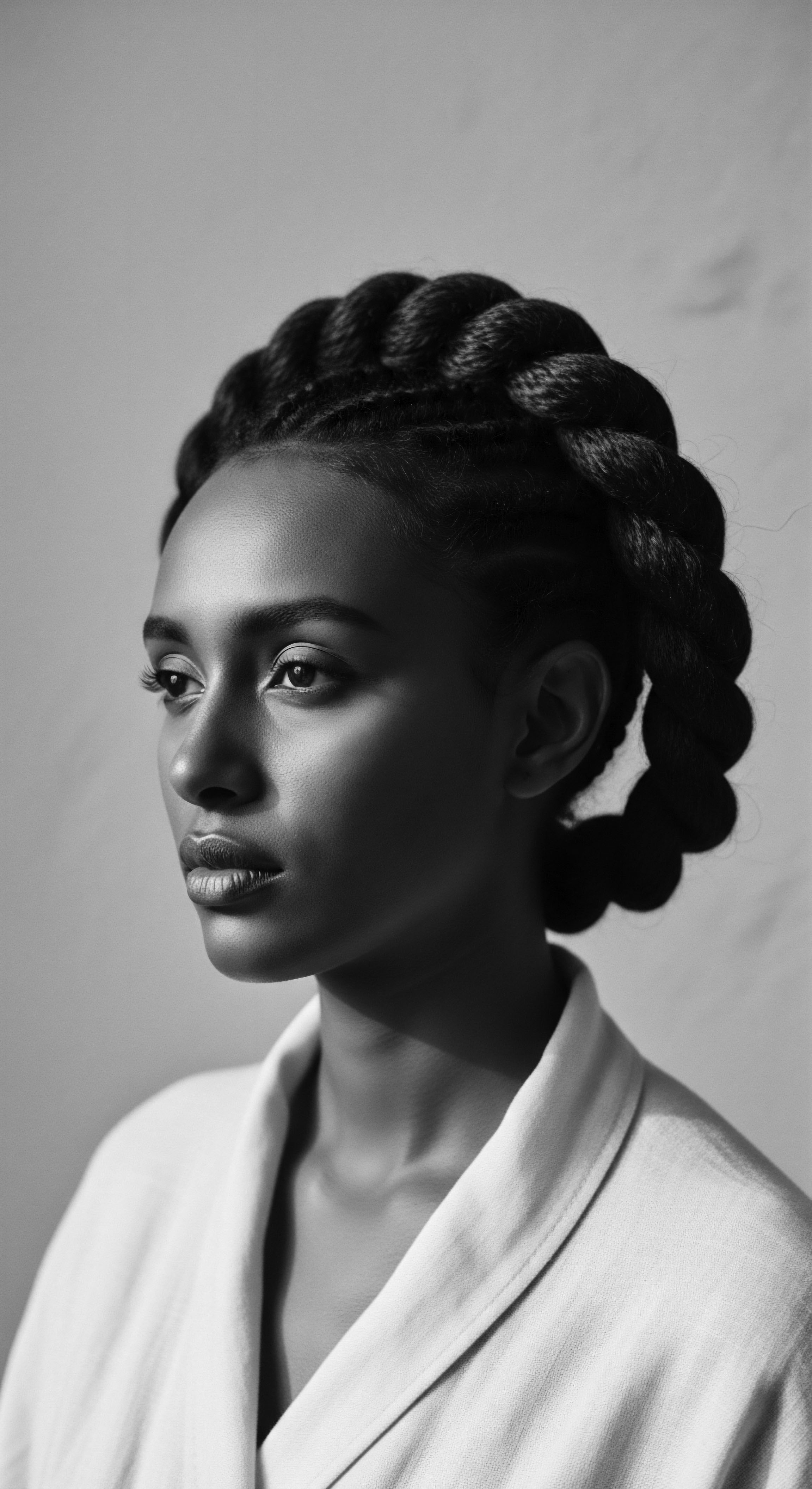 Elegant Braided Hairstyle Radiating Natural Beauty and Cultural Identity in Black and White This captivating portrait celebrates the artistry of braided hairstyles as expressions of cultural identity and personal strength. The halo braid symbolizes beauty, resilience, and timeless elegance, reflecting the traditions passed down through generations. The monochromatic palette accentuates the intricate details, highlighting the natural elegance of the style.