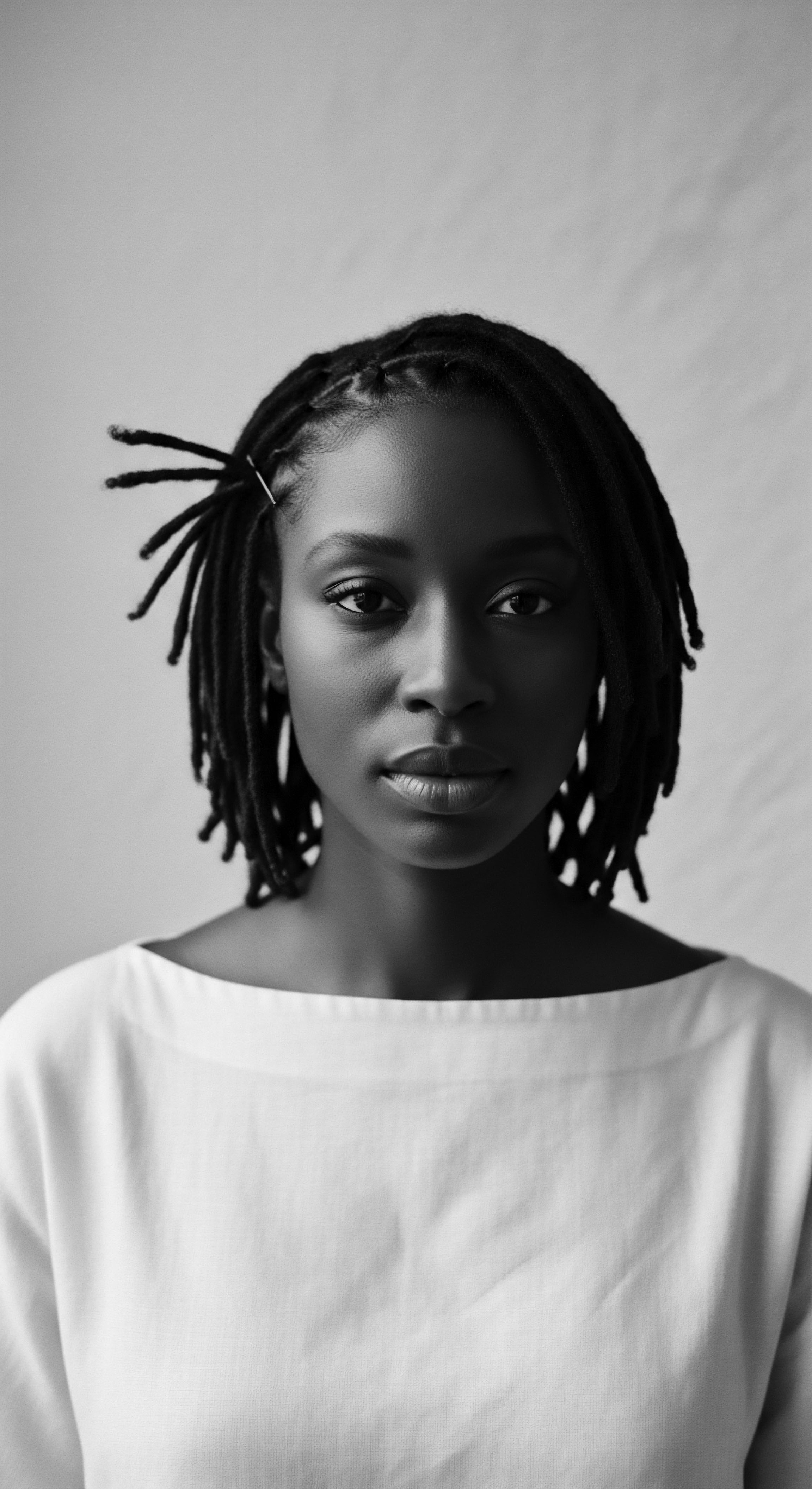 Elegant Portrait of Woman with Locs Showcasing Textured Hair Beauty This portrait embodies cultural expression and strength. Styled locs frame the subject’s thoughtful expression, emphasizing her striking facial features and cultural richness. The portrait serves as a meditation on self-acceptance, ancestral heritage, and the beauty found in natural textured hair formations.