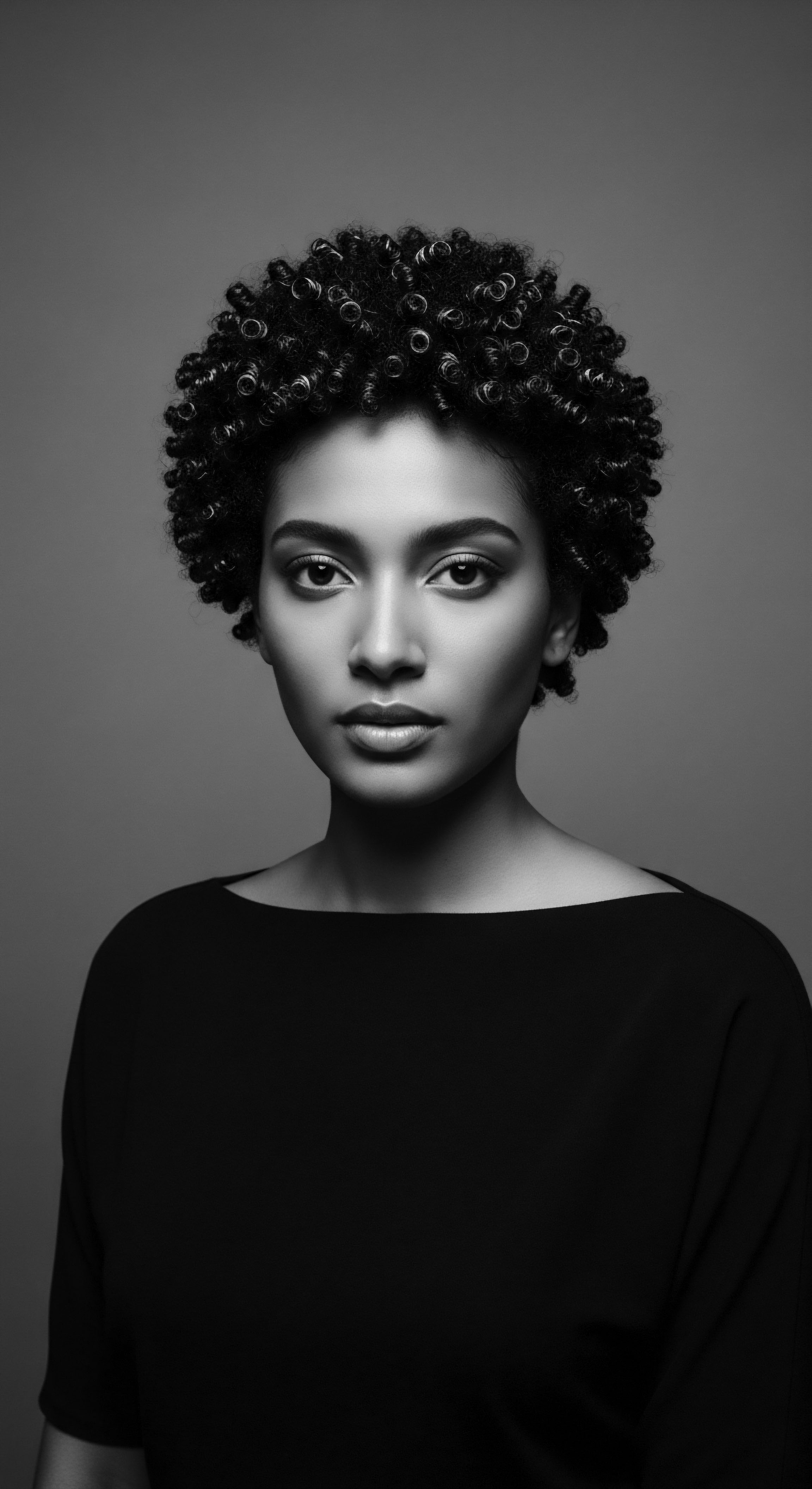 Elegant Portrait of Woman with Natural Coiled Hair and Timeless Style This timeless portrait celebrates natural coiled hair, emphasizing its unique spring-like texture and form. The composition invites viewers to contemplate the artistry and cultural significance inherent in embracing and showcasing authentic Black hair traditions with elegance.