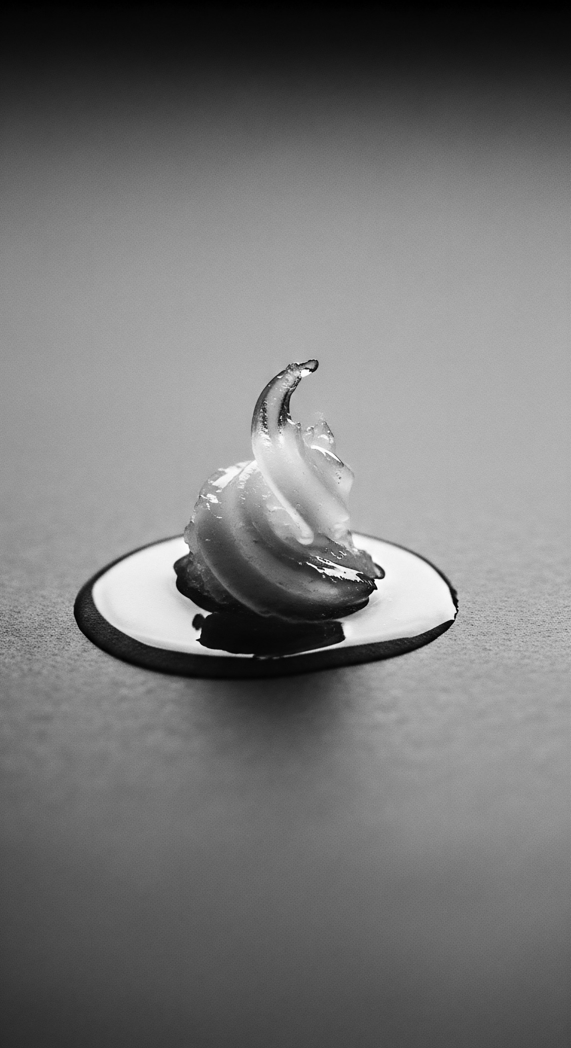 Elegant Swirl of a Textured Hair Product on a Reflective Surface This carefully posed essence embodies a dedication to preserving and enhancing the distinct texture of hair with a treatment rich in natural, beneficial elements, celebrating ancestral beauty traditions through advanced product science and promoting expressive self-care rituals.