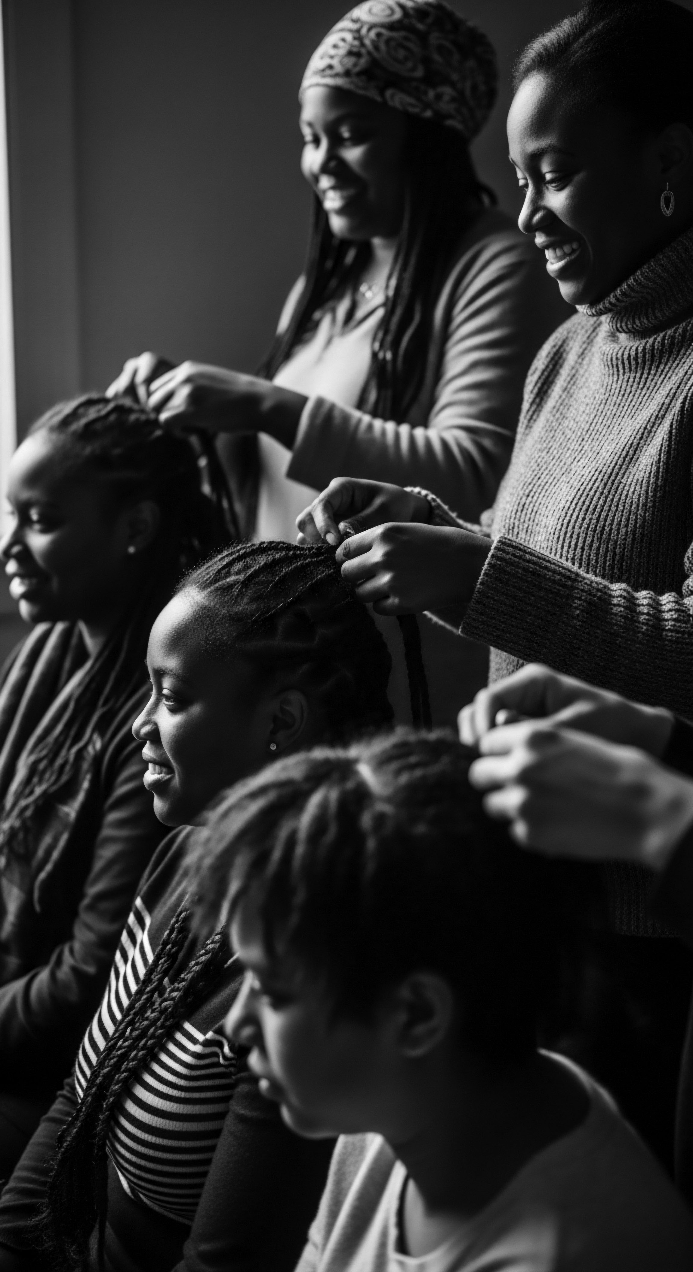 Illuminated by soft light, the intergenerational braiding session unfolds a celebration of Black hair traditions. This intimate act strengthens familial bonds, promotes wellness, and celebrates cultural identity through expert practices passed down offering ancestral pride in the formation of textured hair.