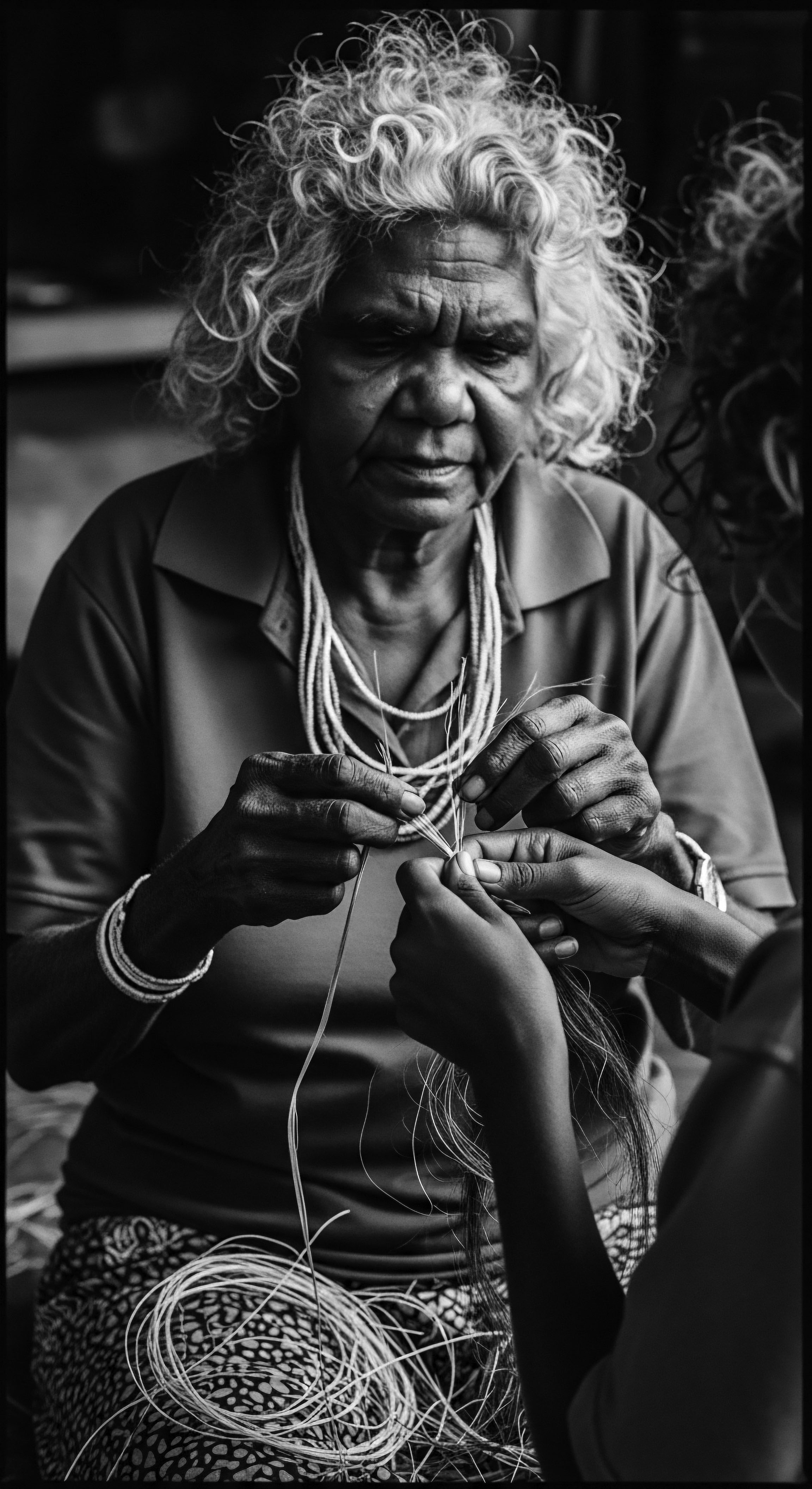 Generational Weaving An Elder’s Hands Instructing Younger Hands on Indigenous Craft Hands intertwined, an elder passes ancestral skills weaving intricate patterns, textured with the rich history of indigenous knowledge. A potent image reflecting dedication to cultural continuity, holistic care, and the preservation of ancestral practices including natural hair maintenance techniques.