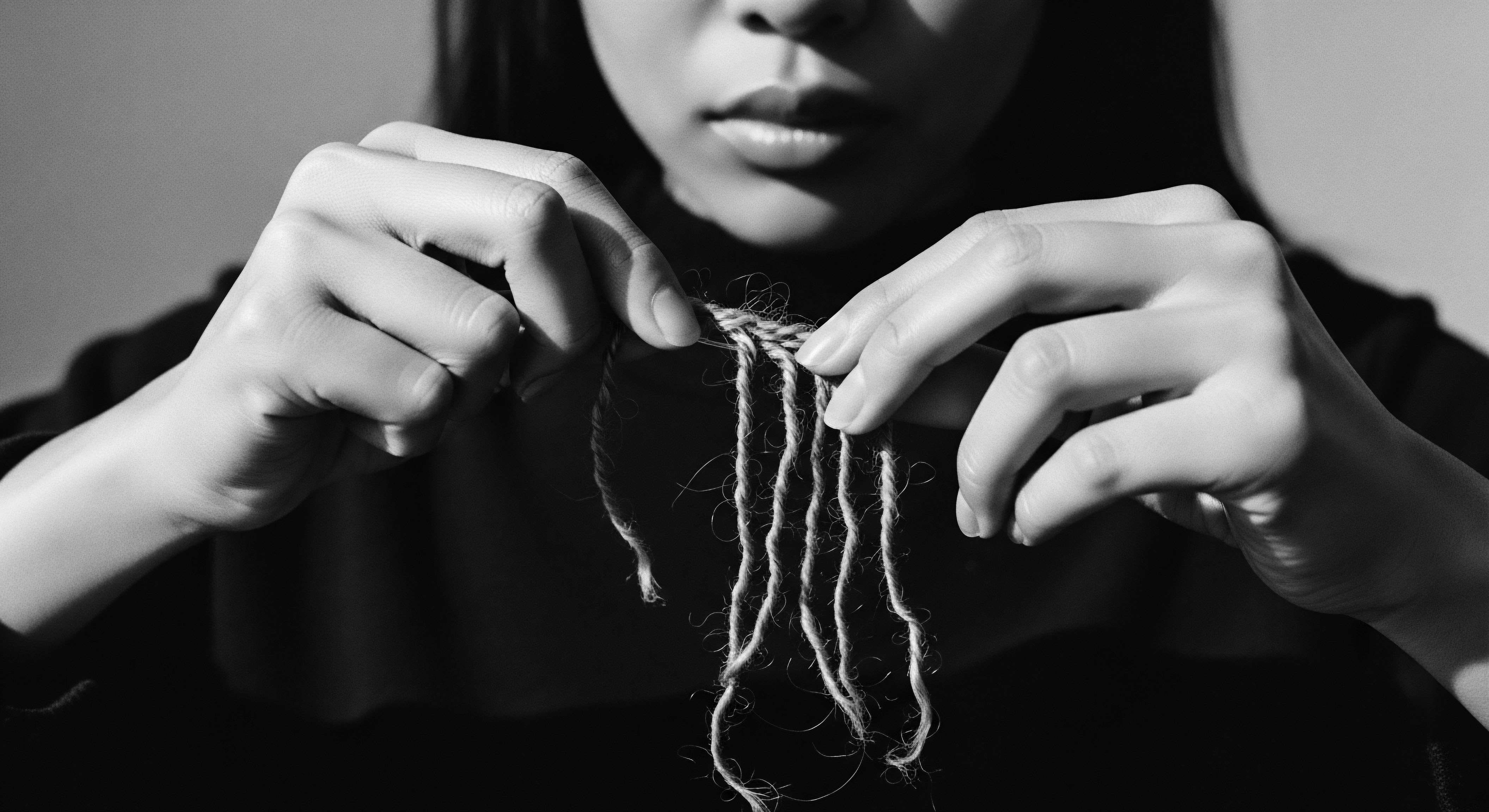 Hands Entwining Natural Fiber Exploring Textured Hair Care Heritage The image captures hands intertwining natural strands, symbolizing the heritage of braiding and threading within textured hair care practices. This close-up reflects holistic wellness approaches and ancestral appreciation for crafting protective formations, celebrating the inherent beauty and power of diverse hair textures.