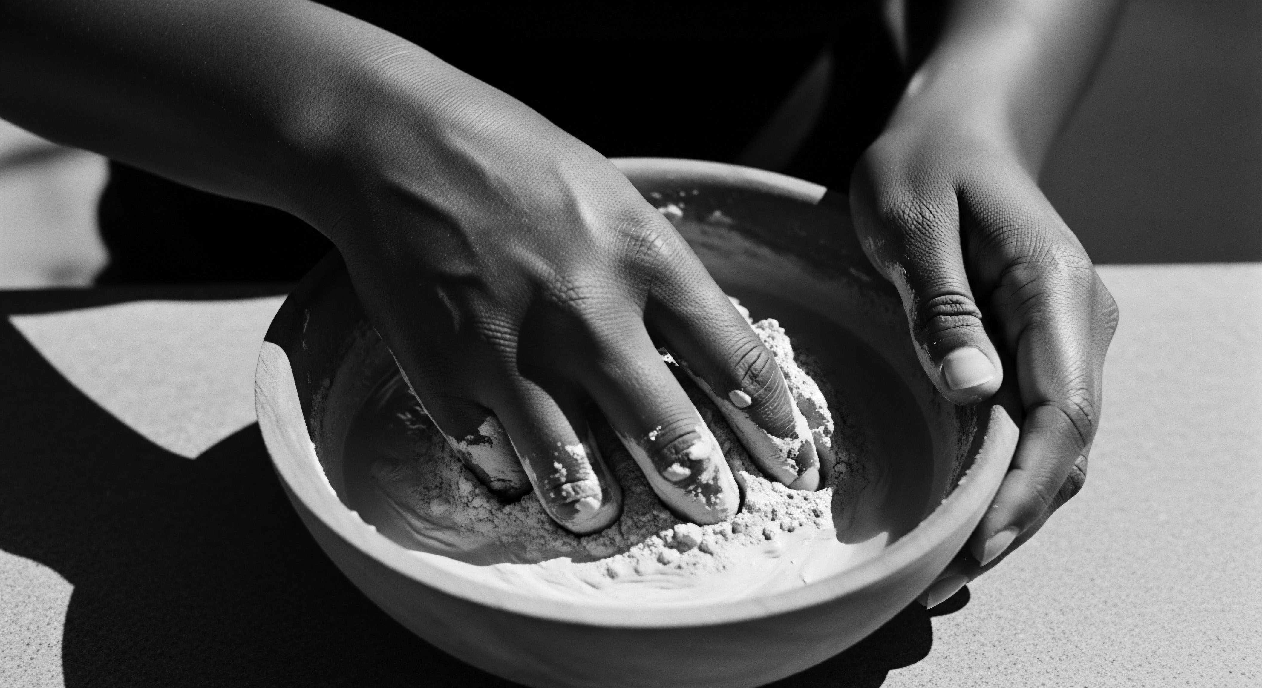 Hands Mixing Clay Mask in Bowl Natural Skincare Holistic Wellness Hands immersed in mixing a clay mask speaks to an ancestral heritage ritual for holistic wellness. The play of light defines the hands' contours, underscoring the tactile engagement with natural elements, inviting a connection to self-care rooted in earthen traditions.