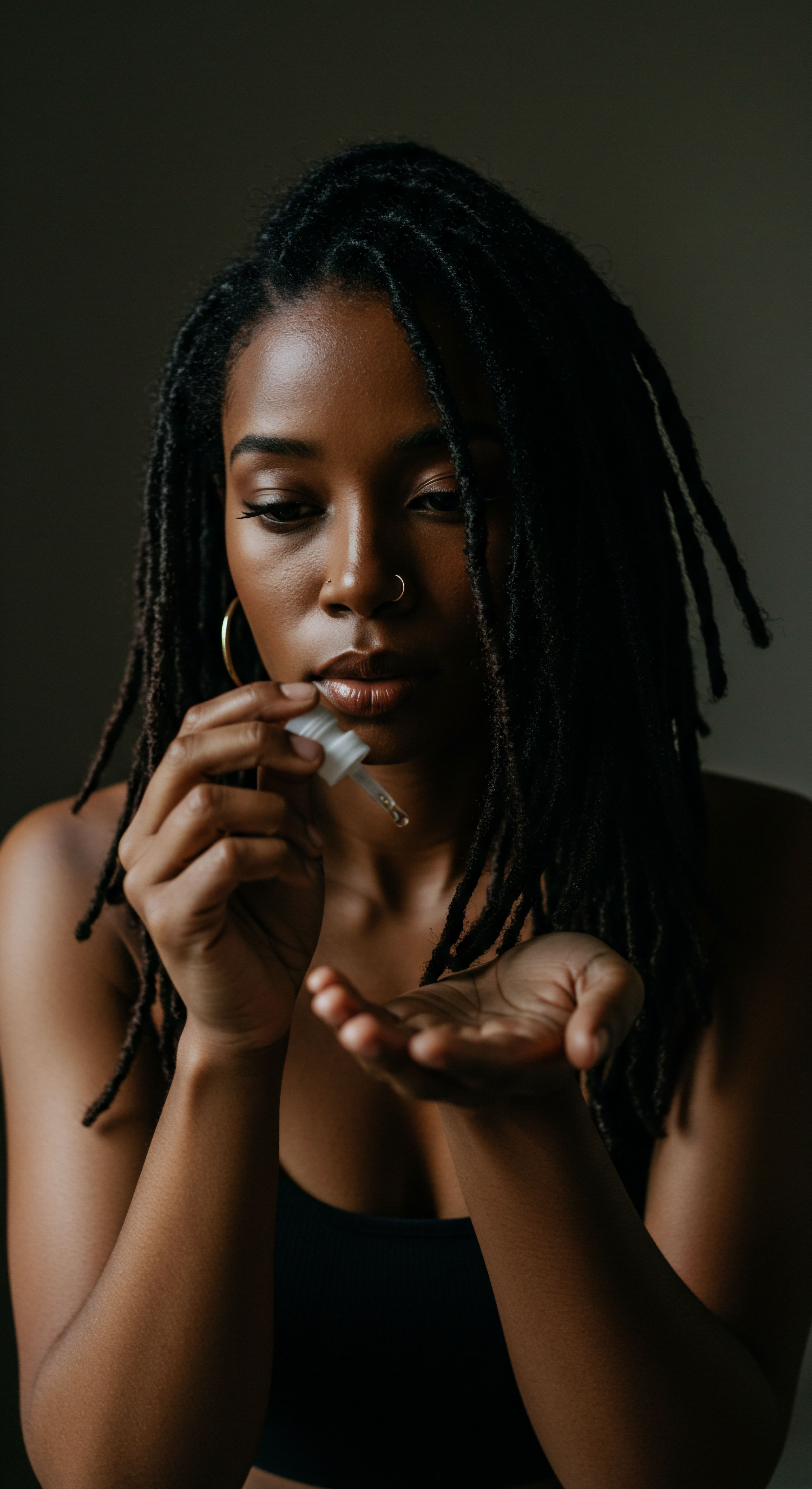 Holistic Hair Care Ritual for Coiled Textured Hair Locs Nourishment This intimate moment highlights dedicated textured hair care, as a person preps a revitalizing oil for their unique locs. Emphasizing heritage through consistent hydration and scalp health, this purposeful act fosters hair integrity and the beauty of deeply set coiled patterns. It's a true natural hair wellness ritual.