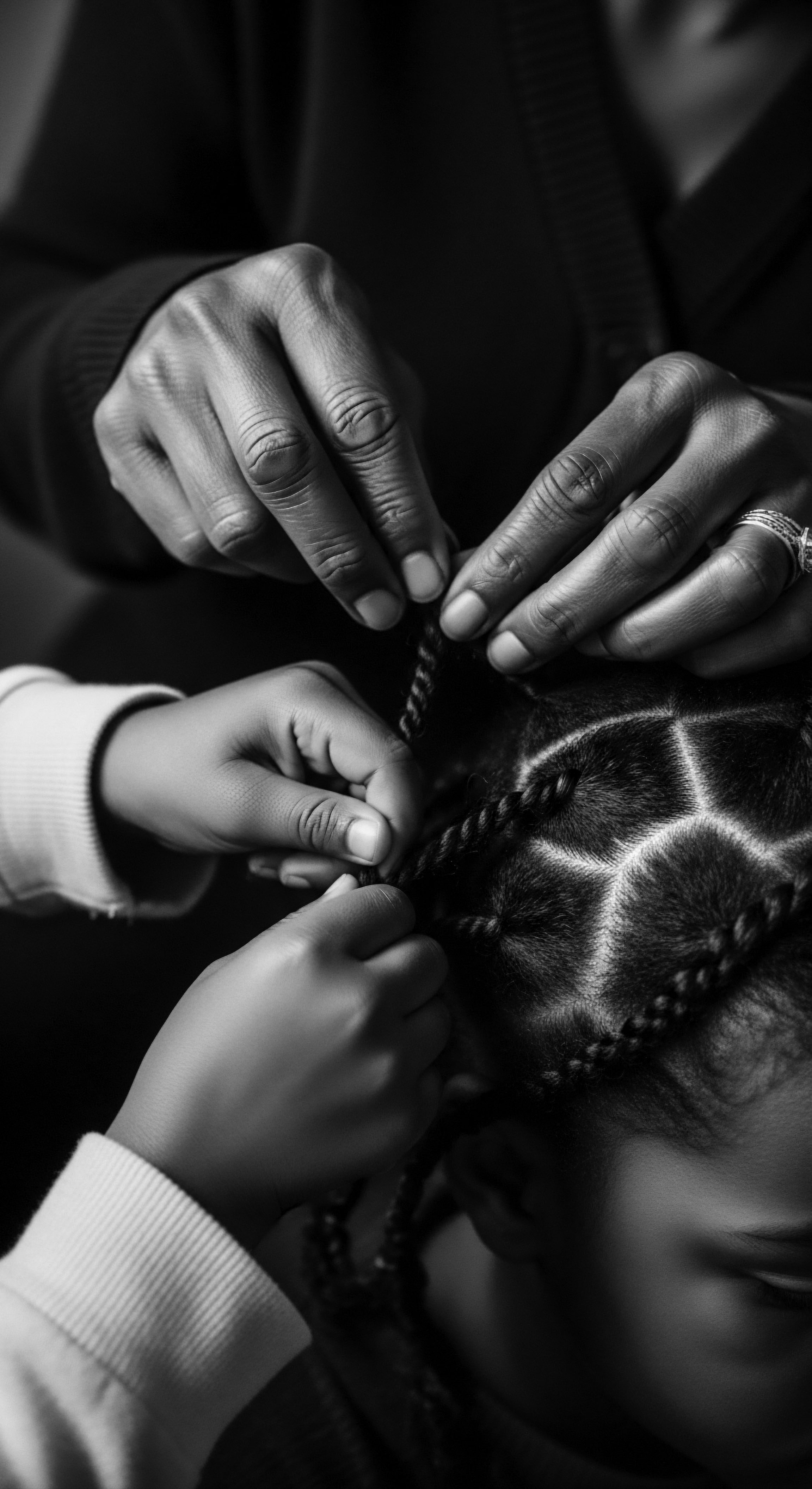Intergenerational Hands Styling Braids Textured Black Hair Heritage Close Up Intergenerational hands intertwine, artfully crafting braids in textured hair, celebrating black hair traditions and promoting wellness through mindful styling. This intimate portrait honors heritage and cultural hair expression, reflecting a legacy of expressive styling, meticulous formation, and protective care.
