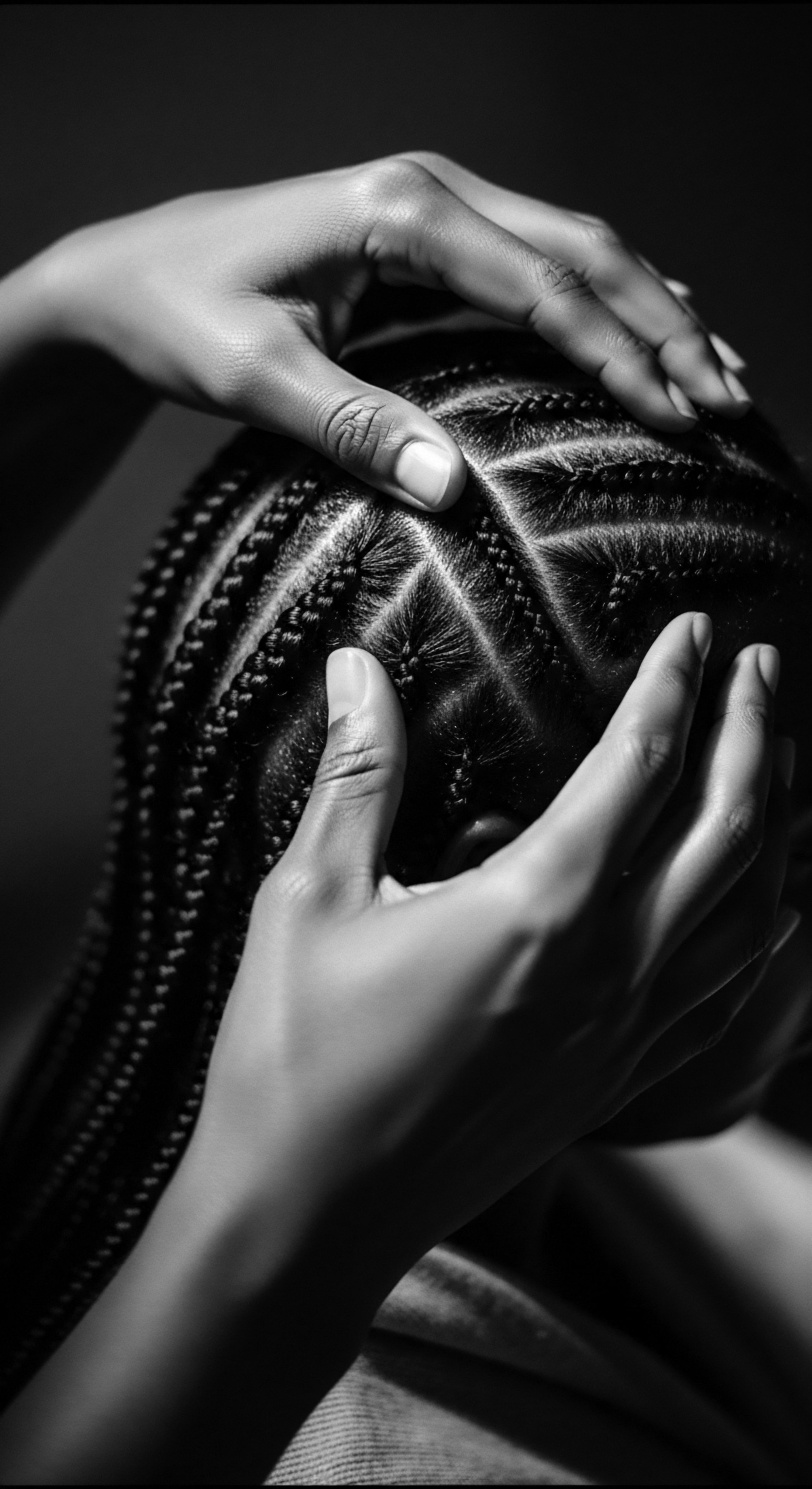 Intricate Cornrow Braids Showcase Heritage and Artistry Textured Hair Design The image captures an intimate moment of connection to heritage through intricate cornrow braiding, showcasing artistry and the deep-rooted cultural significance of textured hair styling. The gentle touch emphasizes the importance of care and ancestral reverence in textured hair traditions.