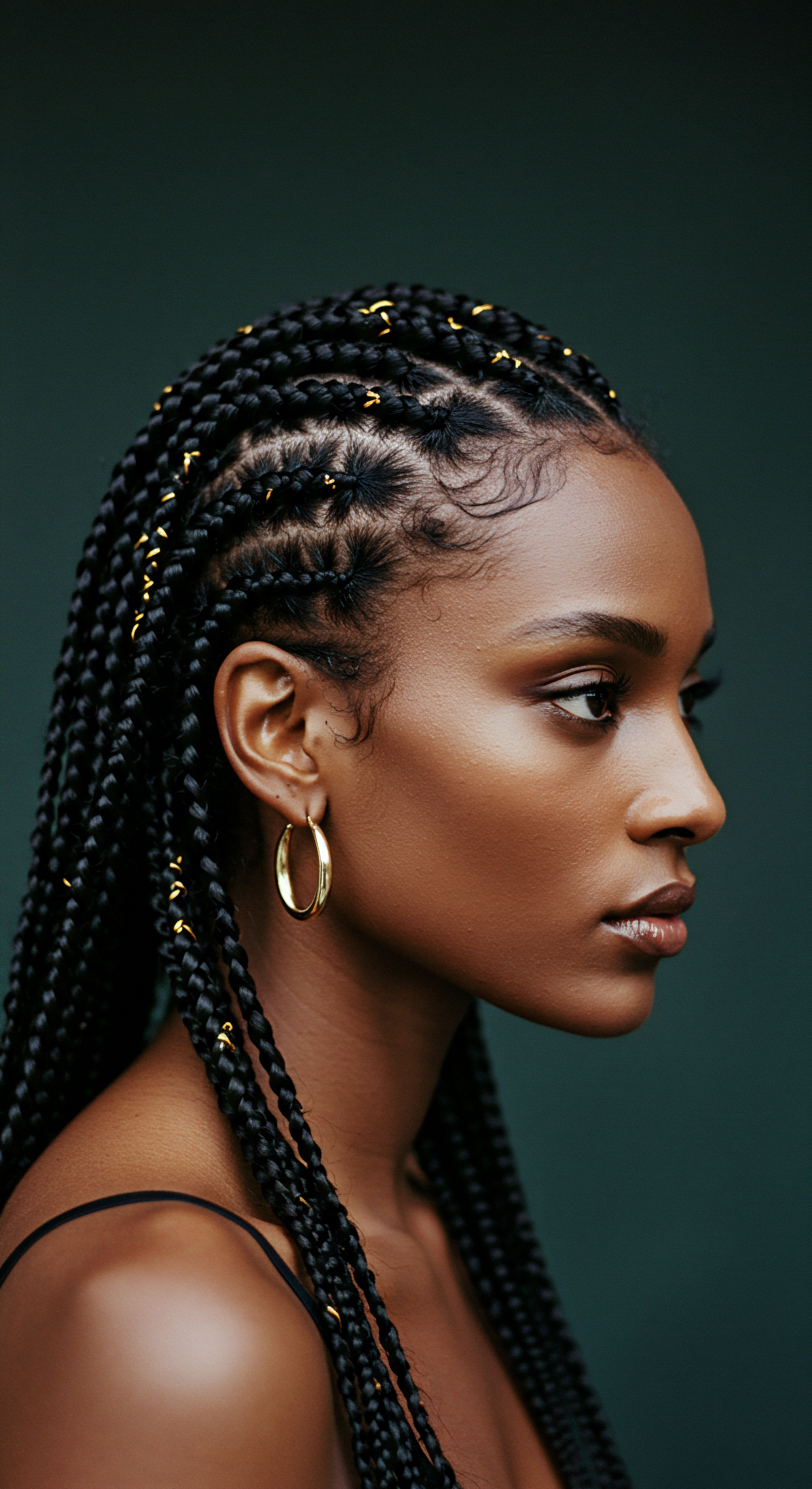 Masterful Box Braids Styling Honoring Afro-Textured Hair Heritage This stunning profile showcases Afro-textured hair styled with cornrow patterns and box braids. Gold hair embellishments and laid edges celebrate cultural heritage and Black hair artistry. This protective styling prioritizes scalp health and moisture retention for coily textures.