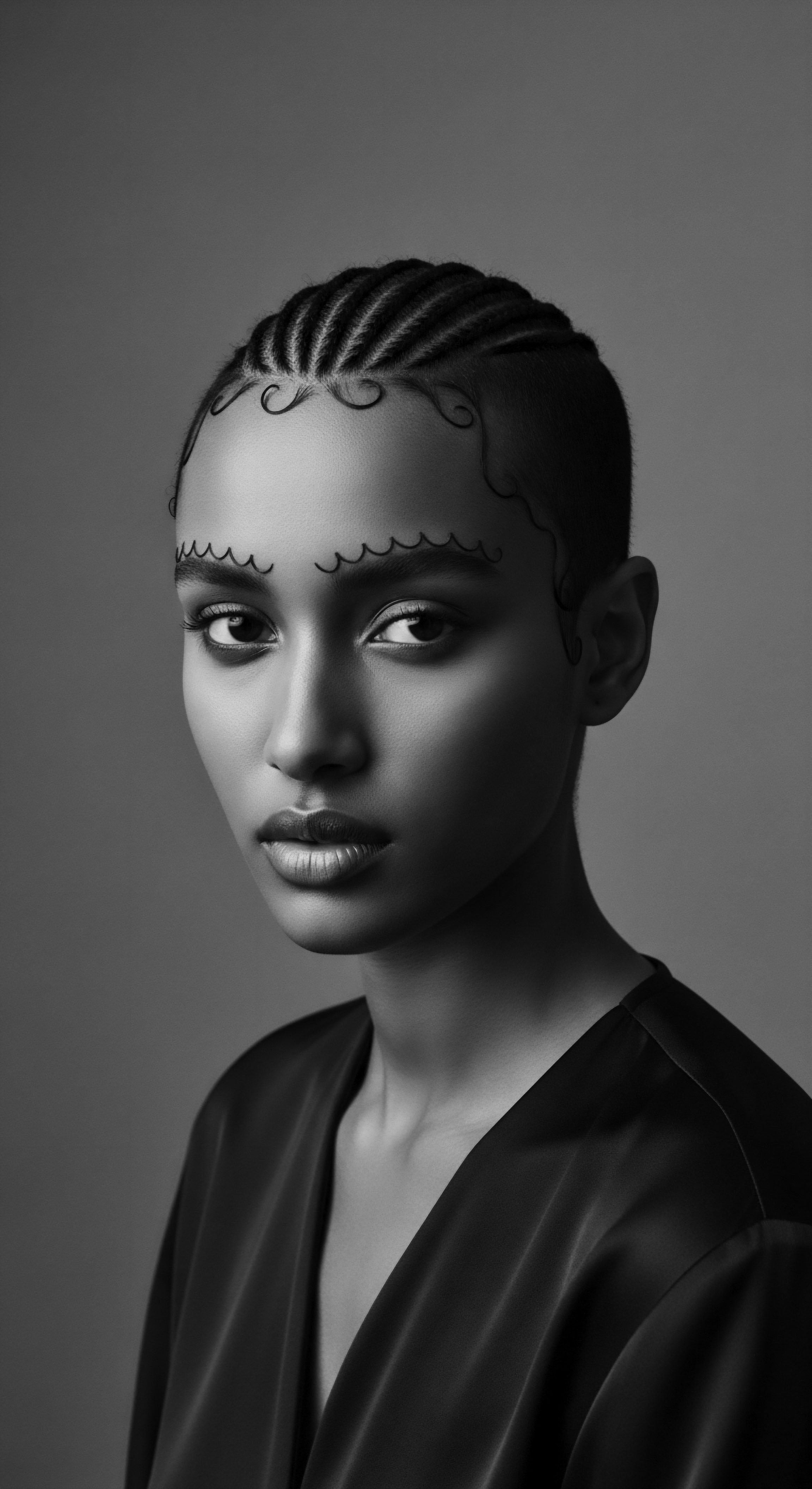 The portrait captures the essence of cultural expression through detailed braiding and stylized edges, the grayscale amplifying the tactile quality of the cornrows. The image resonates with themes of ancestral heritage and the artistry inherent in Black hair traditions, a visual testament to holistic hair care and expressive styling in a mixed-race narrative.