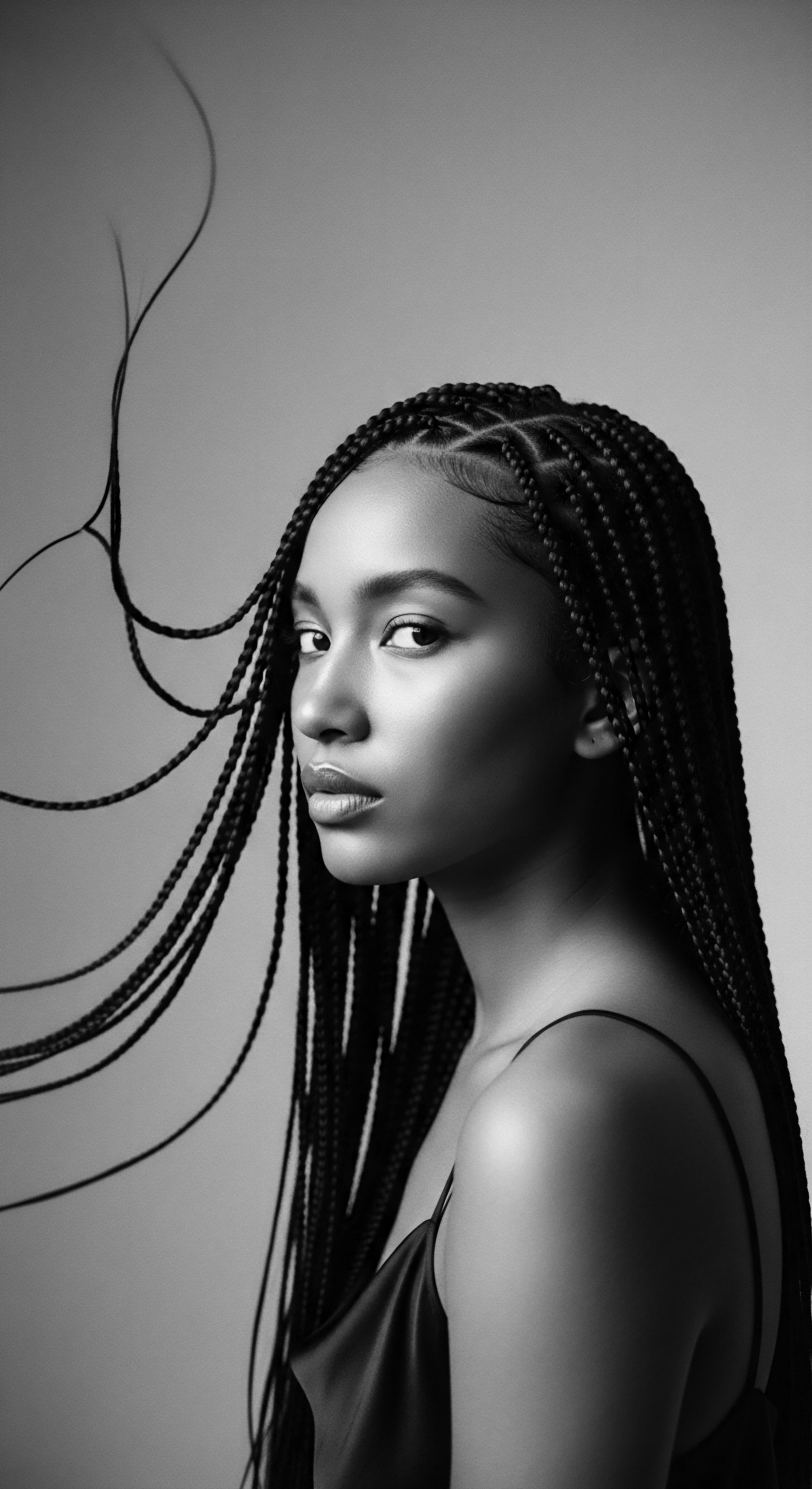Monochromatic Portrait of a Woman with Braided Textured Hair Beauty The monochrome portrait celebrates the beauty of braided textured hair, echoing ancestral strength and cultural expression. The meticulous braiding technique highlights the diverse styling possibilities within Black hair traditions, while the subject's gaze embodies resilience and a deep connection to heritage through thoughtful expressive styling choices and holistic hair care philosophies.