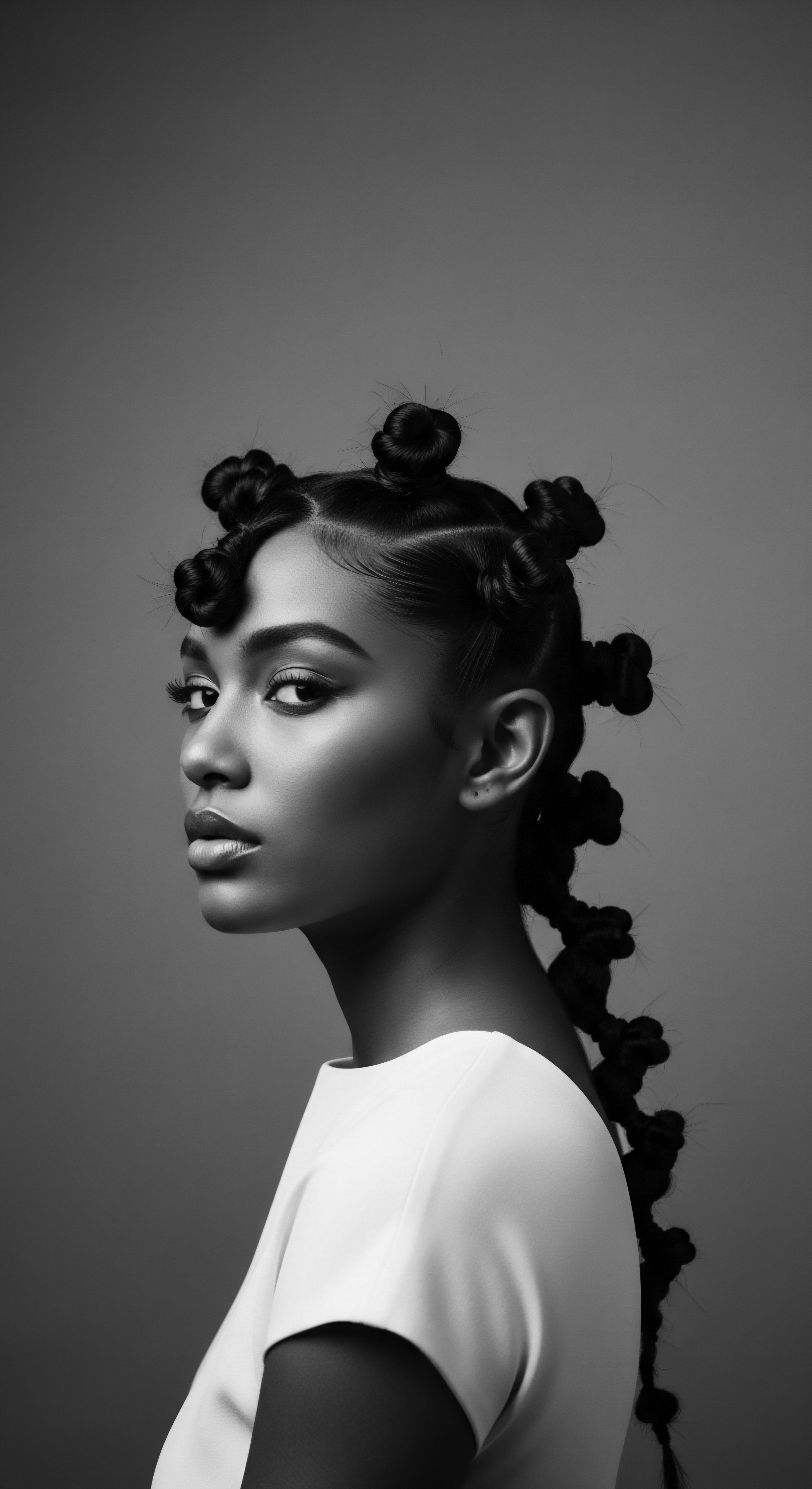 This striking monochrome portrait celebrates the artistry of textured hair, skillfully fashioned into sculpted buns and braids, a testament to ancestral heritage and personal expression. The woman's direct gaze and elegant presentation underscore themes of identity and cultural pride, highlighting the inherent beauty and versatility of Black hair forms.