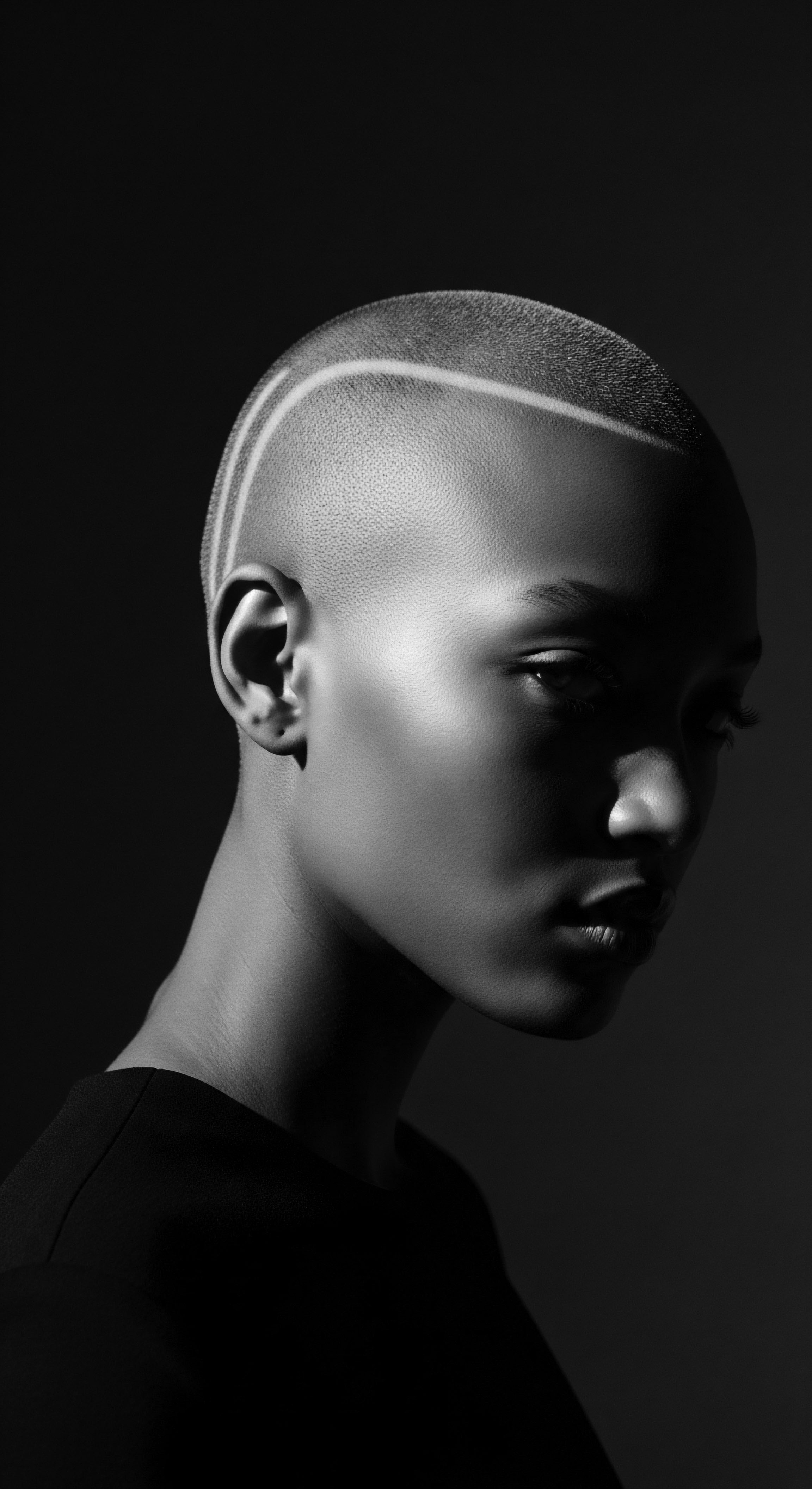 Monochrome Portrait of Bald Black Woman with Geometric Hair Marking The image evokes the strength and beauty in natural simplicity, spotlighting a unique textured scalp design that enhances her bold appearance. It celebrates the freedom of Black identity through expressive styling, a tribute to ancestral roots and progressive self-care philosophies.