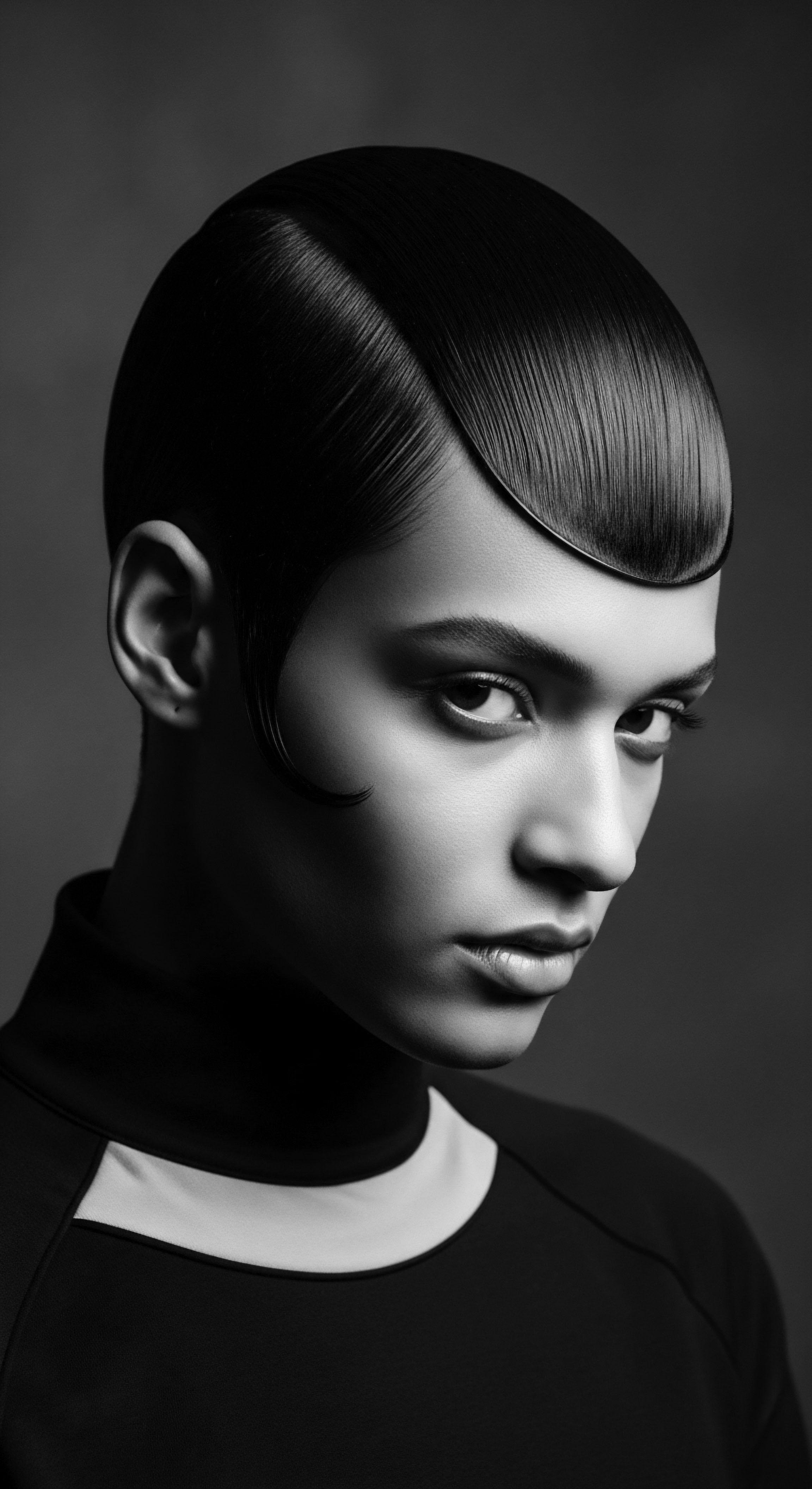 This monochrome study captures the essence of modern hairstyling, emphasizing sleek lines and glossy finishes that showcase the woman's meticulously styled short textured hair. It's a fusion of beauty and technical artistry, celebrating the rich history of sculpted hair forms and contemporary elegance.
