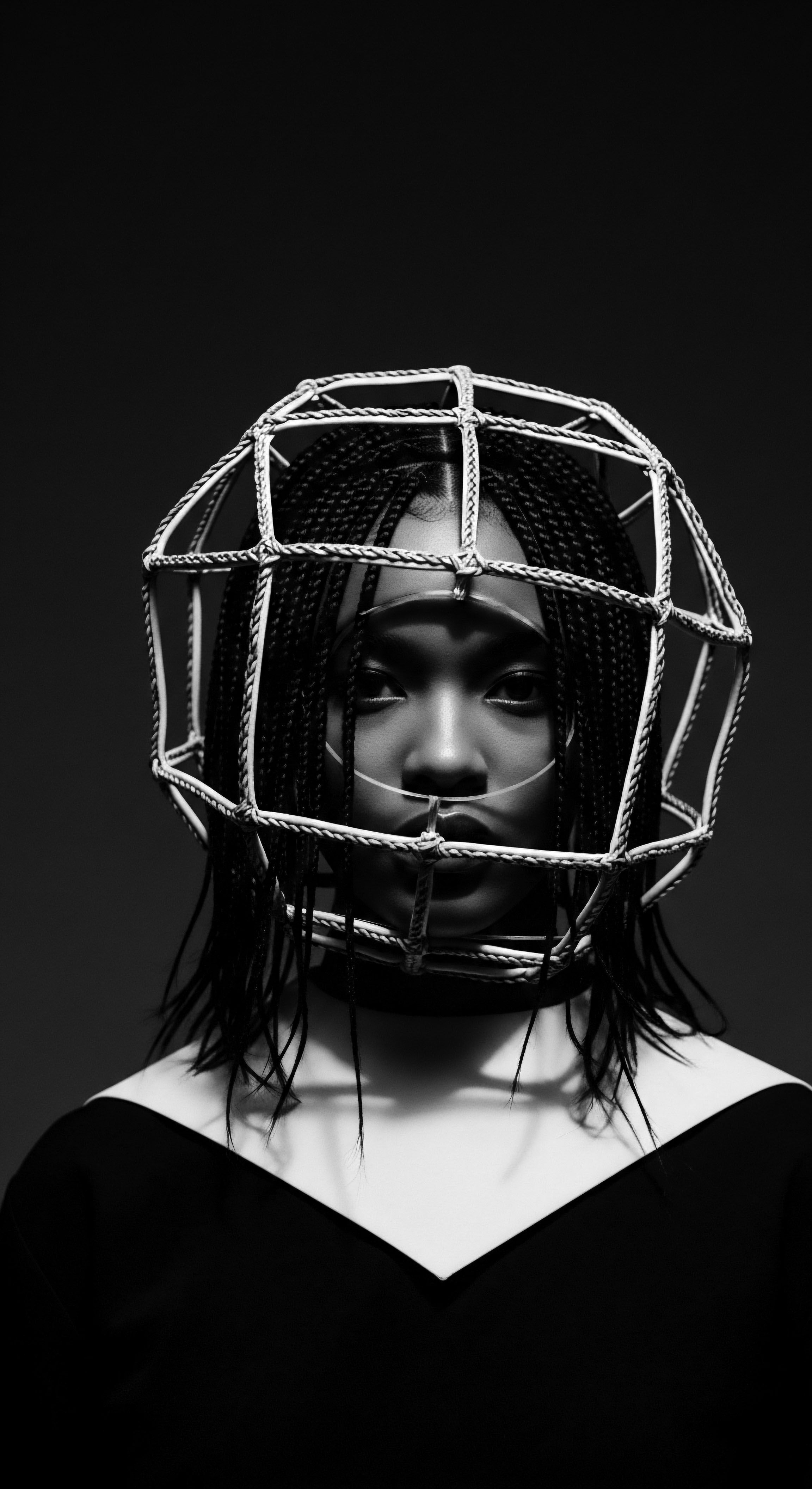 Monochrome Portrait of Woman with Braided Hair and Wireframe Headpiece This captivating monochrome image elevates textured hair through the structural headpiece, presenting a compelling perspective on ancestral heritage and expressive styling. It encourages contemplation on how individual style can reflect both personal identity and broader narratives of resilience, wellness, and self-expression.