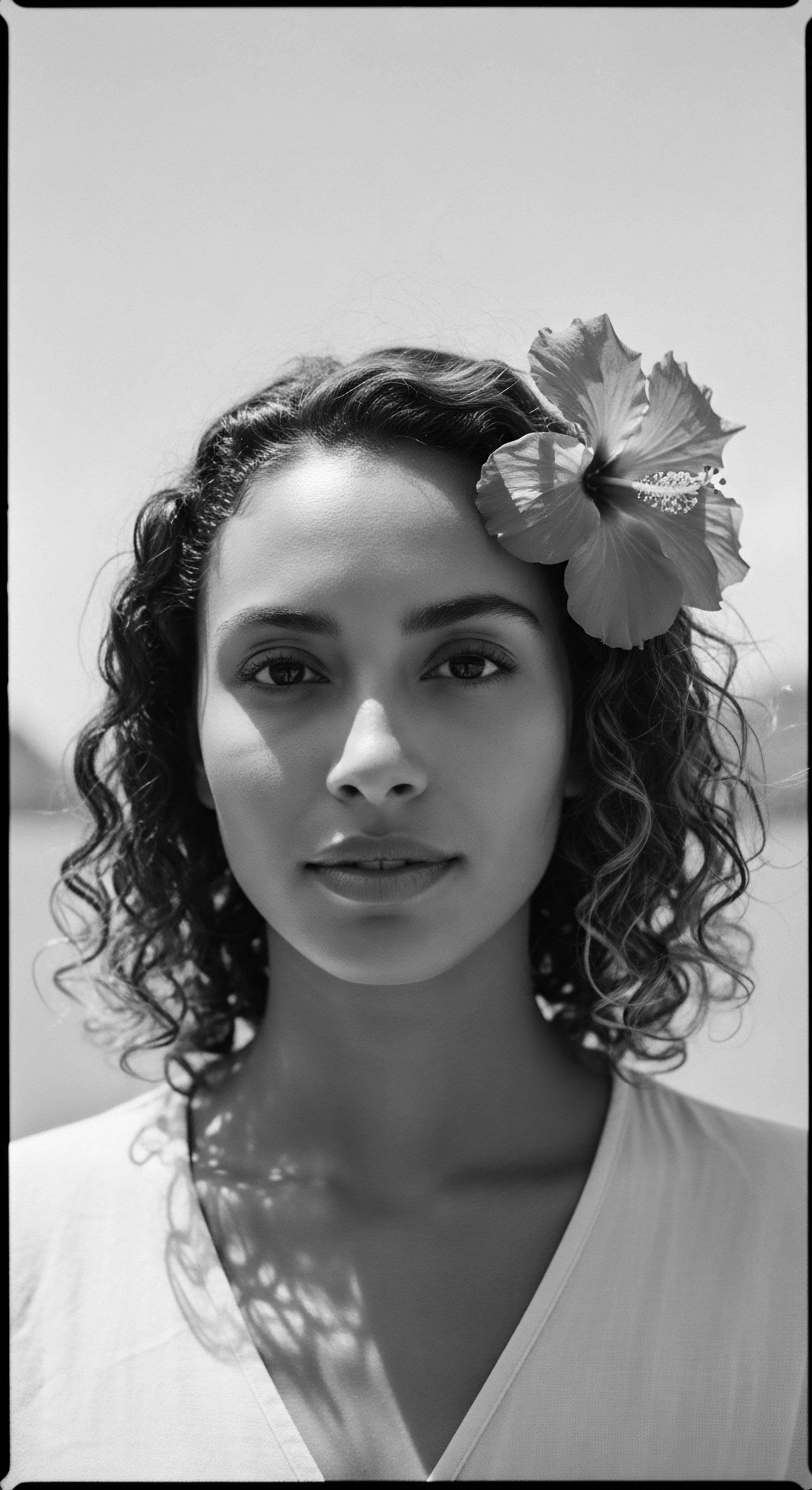 Monochrome Portrait Woman Adorned with Hibiscus Flower Exploring Textured Hair Heritage Bathed in soft monochrome, the subject with expertly styled coiled hair and a hibiscus blossom evokes heritage through mindful grooming practices the portrait celebrates textured hair’s story of resilience, individuality and beauty. This image is a narrative of self-discovery, self-love, and cultural pride, showcasing wellness.