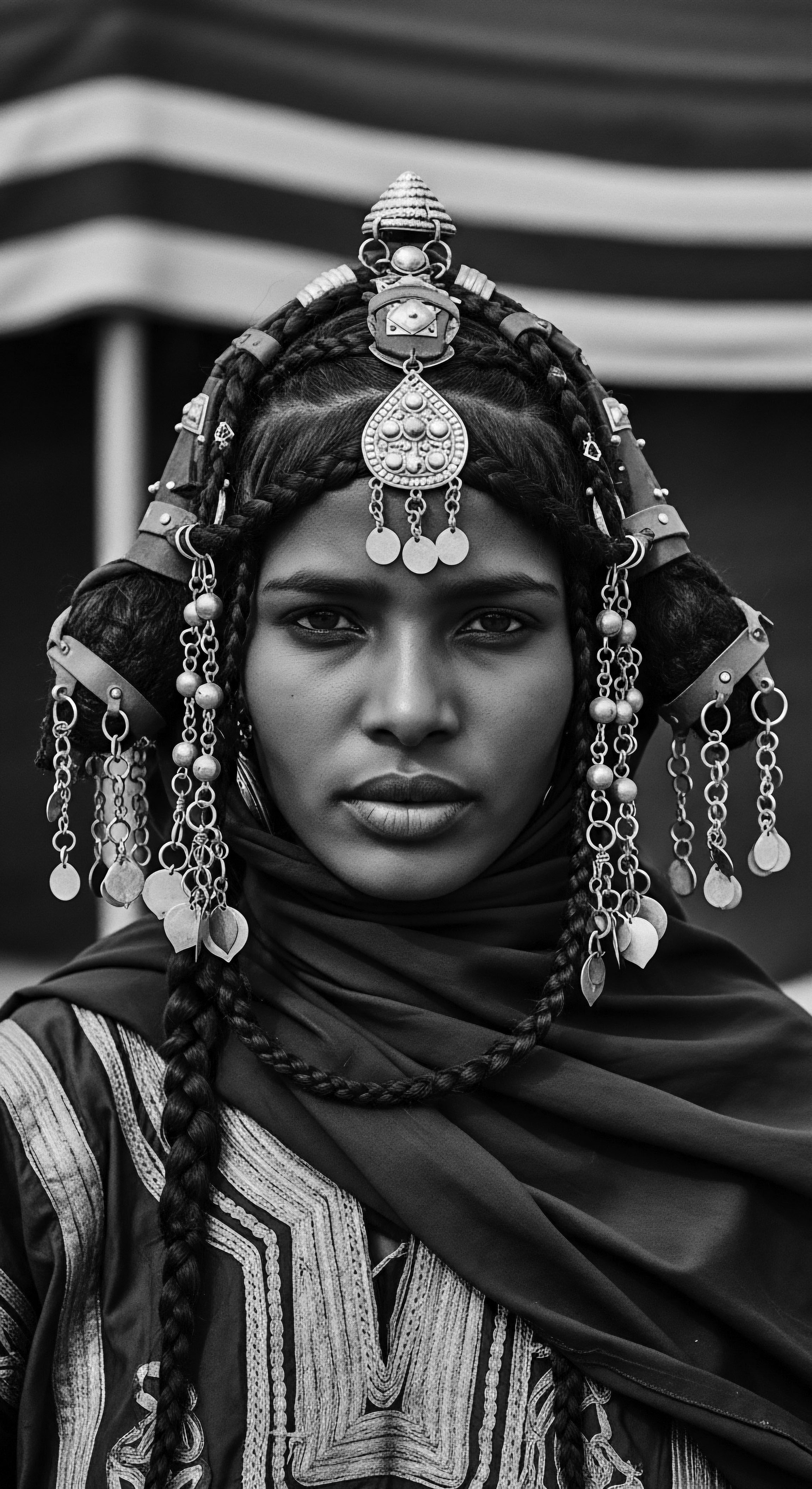 Moroccan Woman Adorned in Traditional Headdress Black and White Portrait This portrait preserves a moment of heritage, the traditional headdress speaking to cultural identity and a lineage of artistry. The woman's serious expression invites consideration of the deep connection between adornment, self-expression, and collective memory through her textured hair.