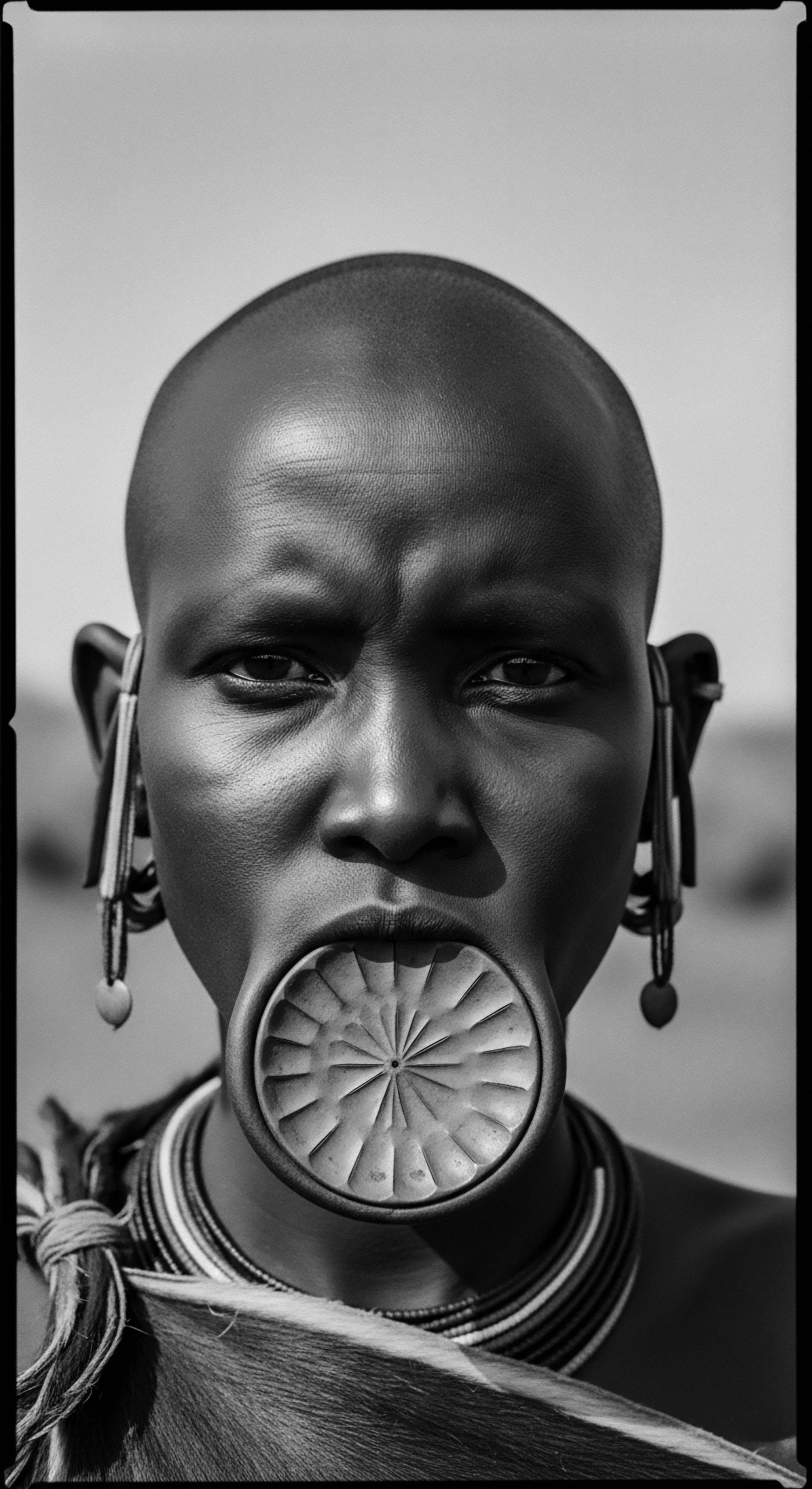 Mursi Woman Black and White Portrait Lip Plate Tribal Adornment This image presents the cultural practices and indigenous beauty of a Mursi woman, emphasizing the symbolism of her unique tribal adornments. It is a visual exploration of identity and ancestral traditions, highlighting the intricate beauty of the Mursi people.