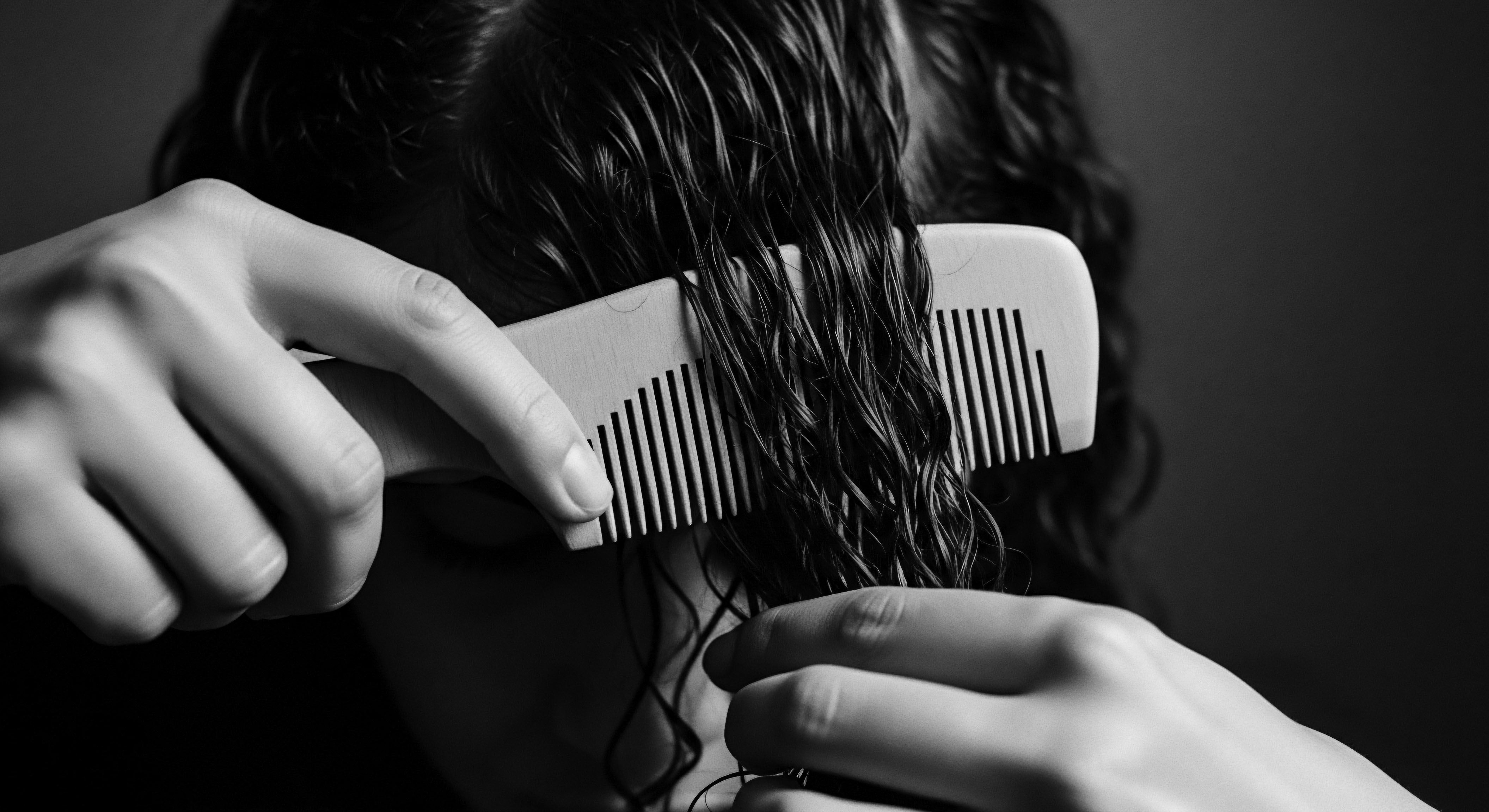 A mindful hand utilizes a comb to carefully detangle wet, textured hair, showcasing a commitment to holistic hair care rooted in ancestral practices. This image captures the dedication to defining and enhancing natural wave patterns, reflecting wellness and deep cultural respect for unique hair heritage.