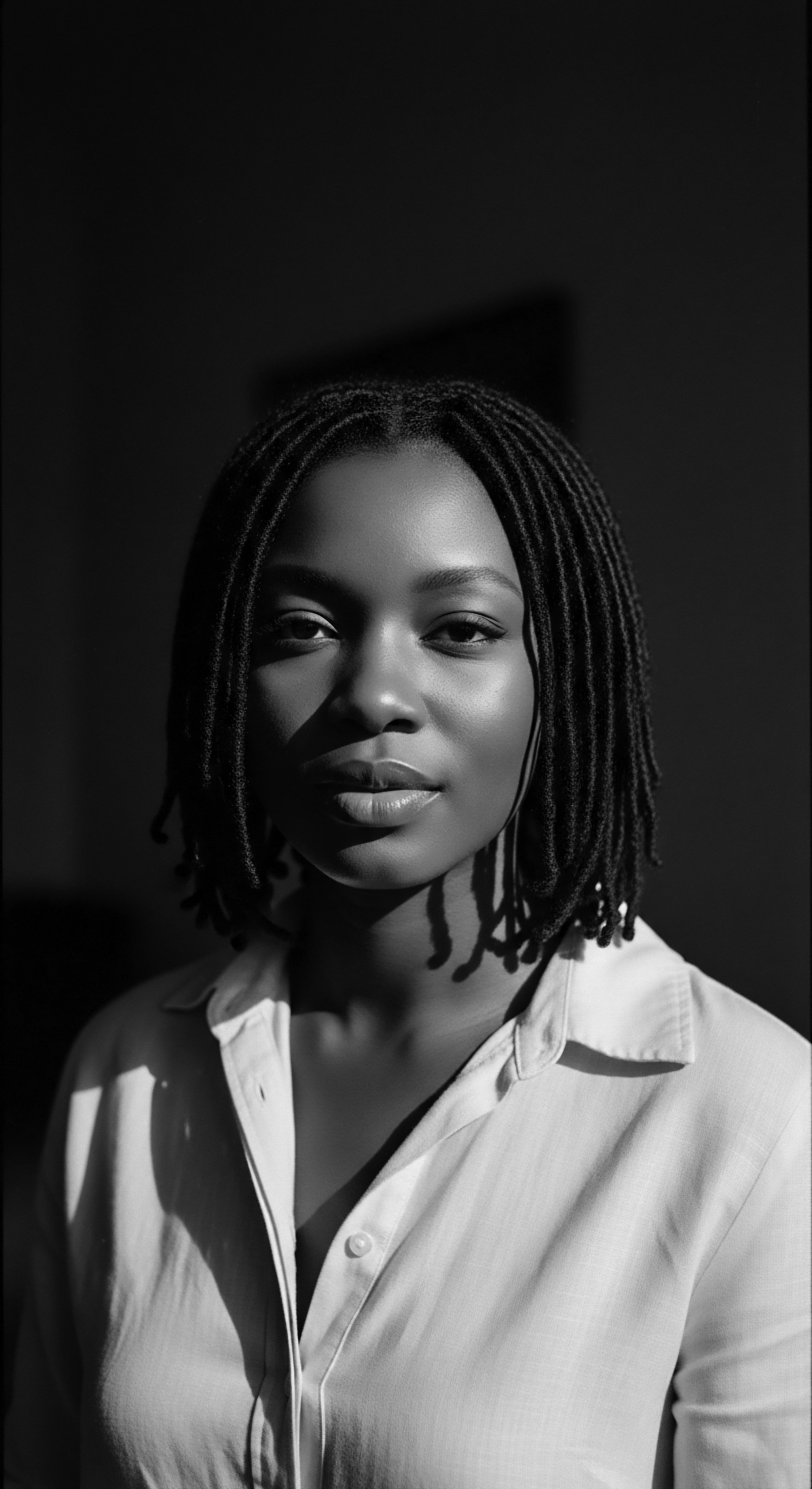 Poised Woman Showcasing Braided Bob Hairstyle in Black and White Portrait Captured in monochrome, the woman radiates poise, her braided hairstyle symbolizing heritage and individuality. The light and shadow play underscore the texture of the hair, inviting contemplation on identity and the art of self-expression through personal grooming.