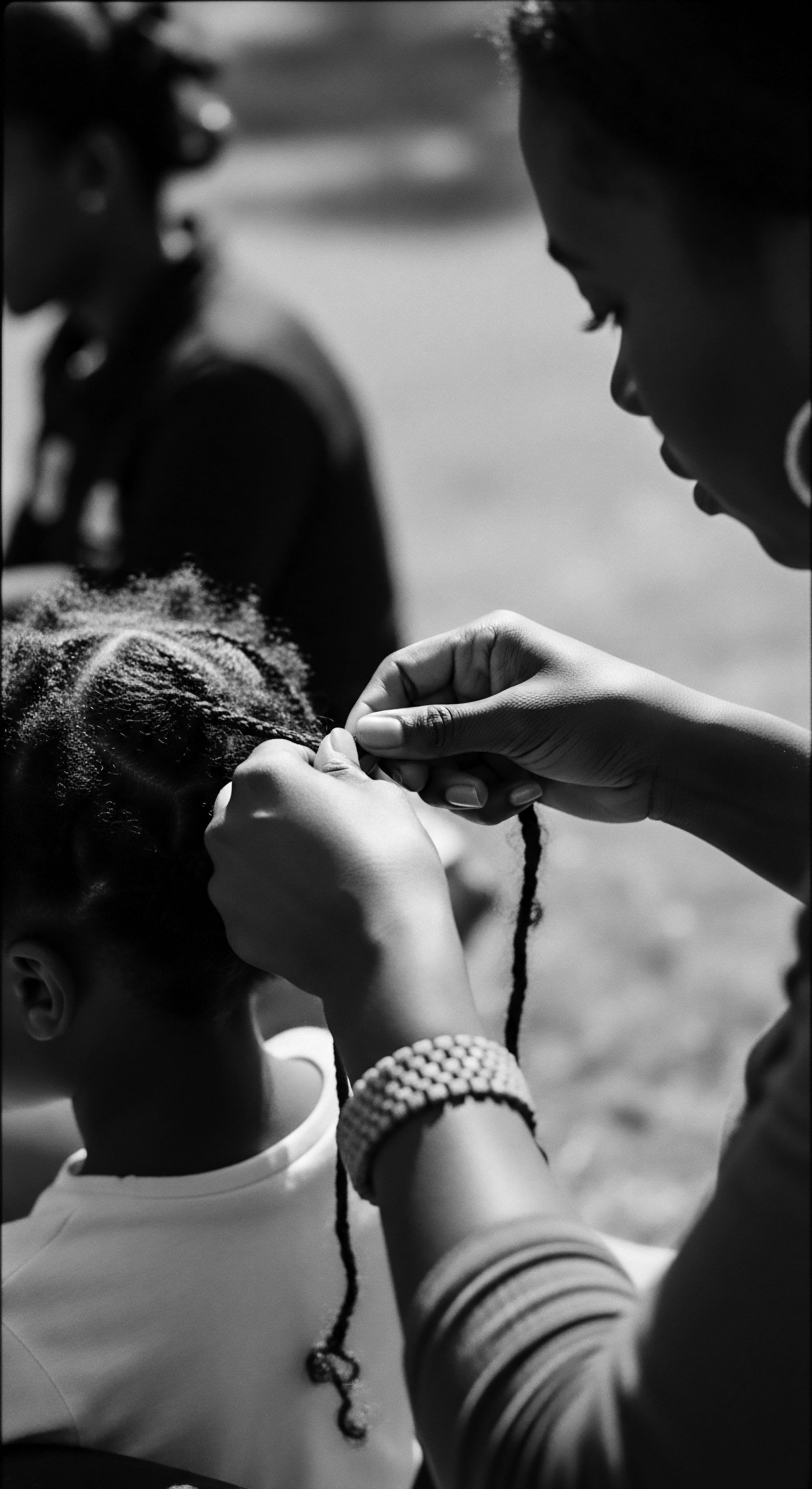 Protective Styling Daughter’s Hair Textured Hair Care and Connection Black Heritage Hands weave intricate patterns into the child's textured hair, celebrating ancestry and the shared ritual. The braided hairstyle embodies cultural heritage, love, and careful attention to the scalp’s wellness as well as an ongoing legacy of holistic textured hair care practices passed down through generations.