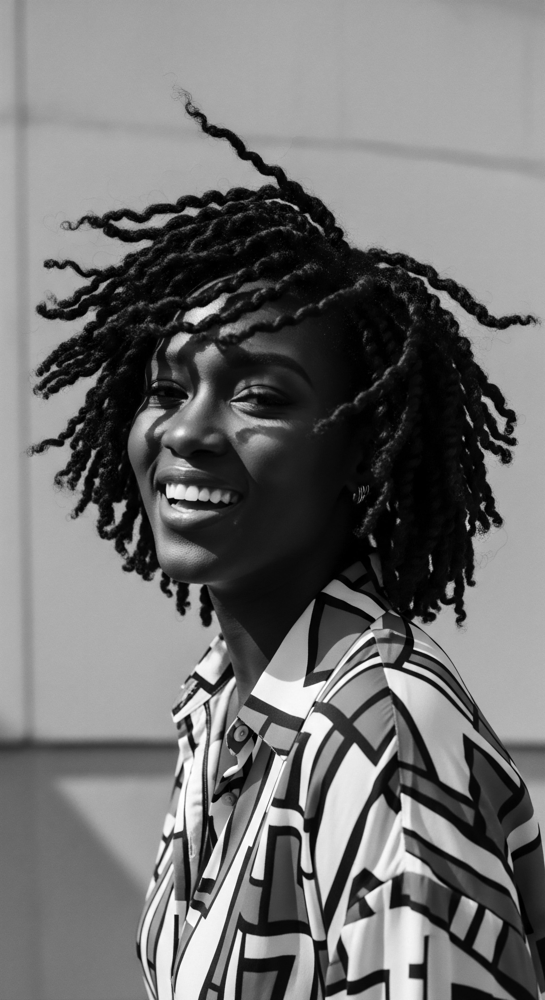 Radiant Woman with Textured Locs Expressing Joy and Cultural Pride The subject's vibrant joy mirrors her dynamic textured locs, demonstrating personal and cultural expression within ancestral pride. The interplay of light accentuates the unique formations of her hair, highlighting both individual beauty and holistic traditions of Black hair styling.