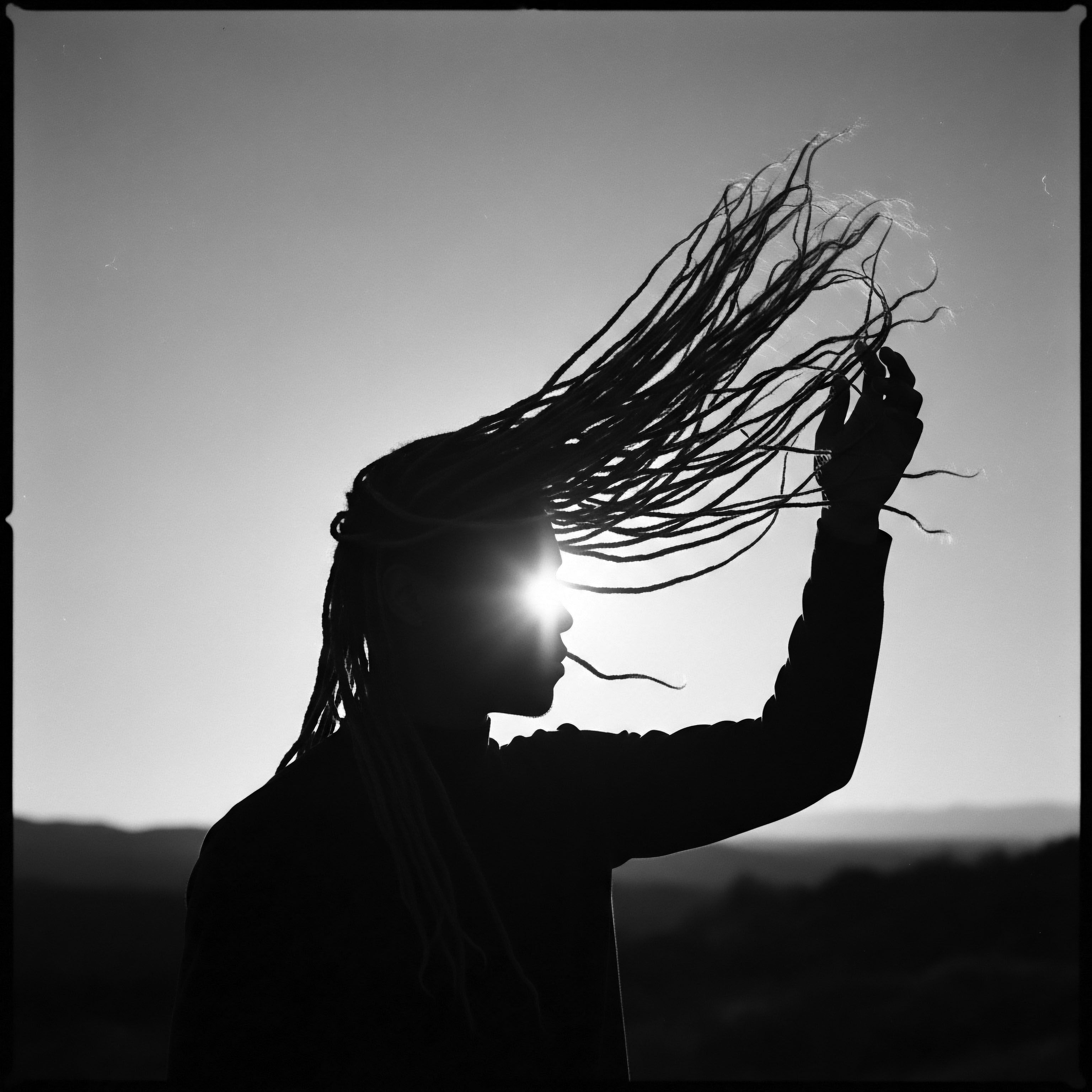 Silhouette of Person with Locs Against Sunlight Revealing Textured Hair Heritage Against a backdrop of sunlit horizons, textured hair in the form of locs is silhouetted, evoking ancestral connections and symbolizing resilience. This image celebrates natural Black hair formations, its beauty, and historical significance in expressive Black cultural identity, wellness, and holistic care through styling.