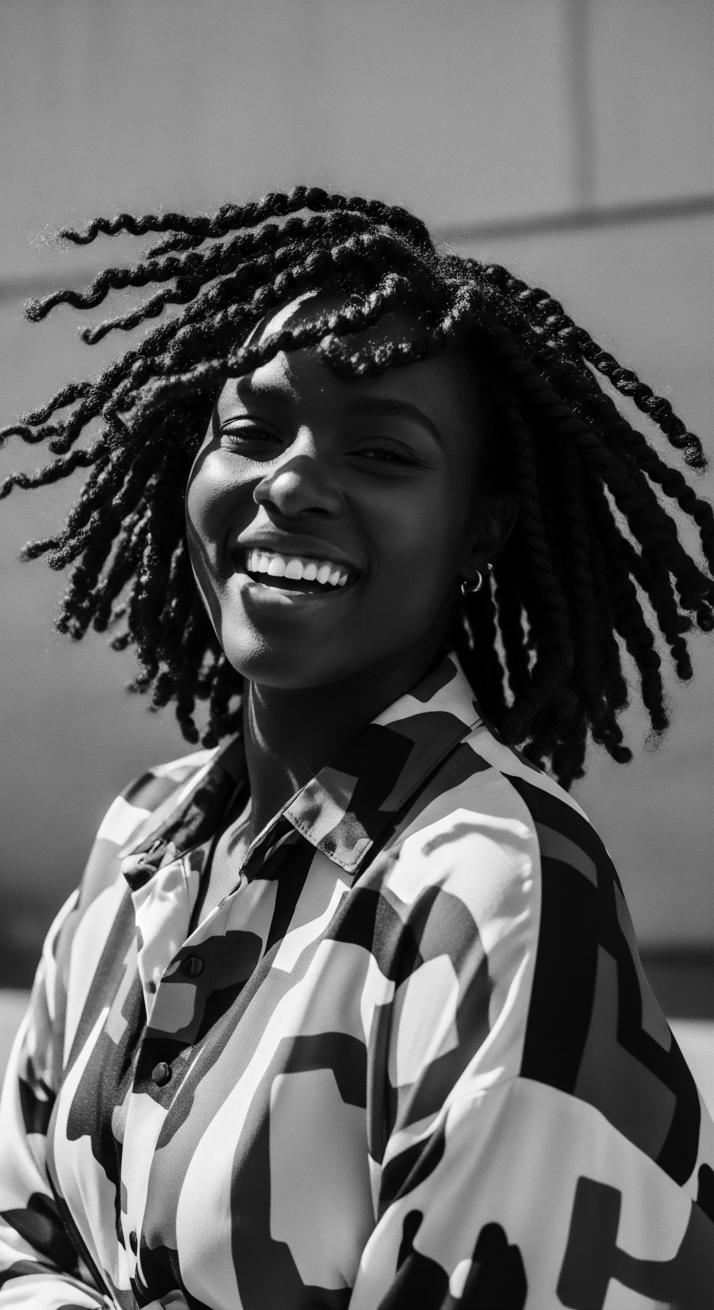 Smiling Black Woman with Locs, Natural Texture and Joyful Expression Sun-kissed skin and a dazzling smile radiate warmth, as her spiraling locs dance around her face, embodying freedom. This black and white portrait serves as a powerful statement of identity, celebrating the beauty of natural hair and individual expression in a culturally relevant context.