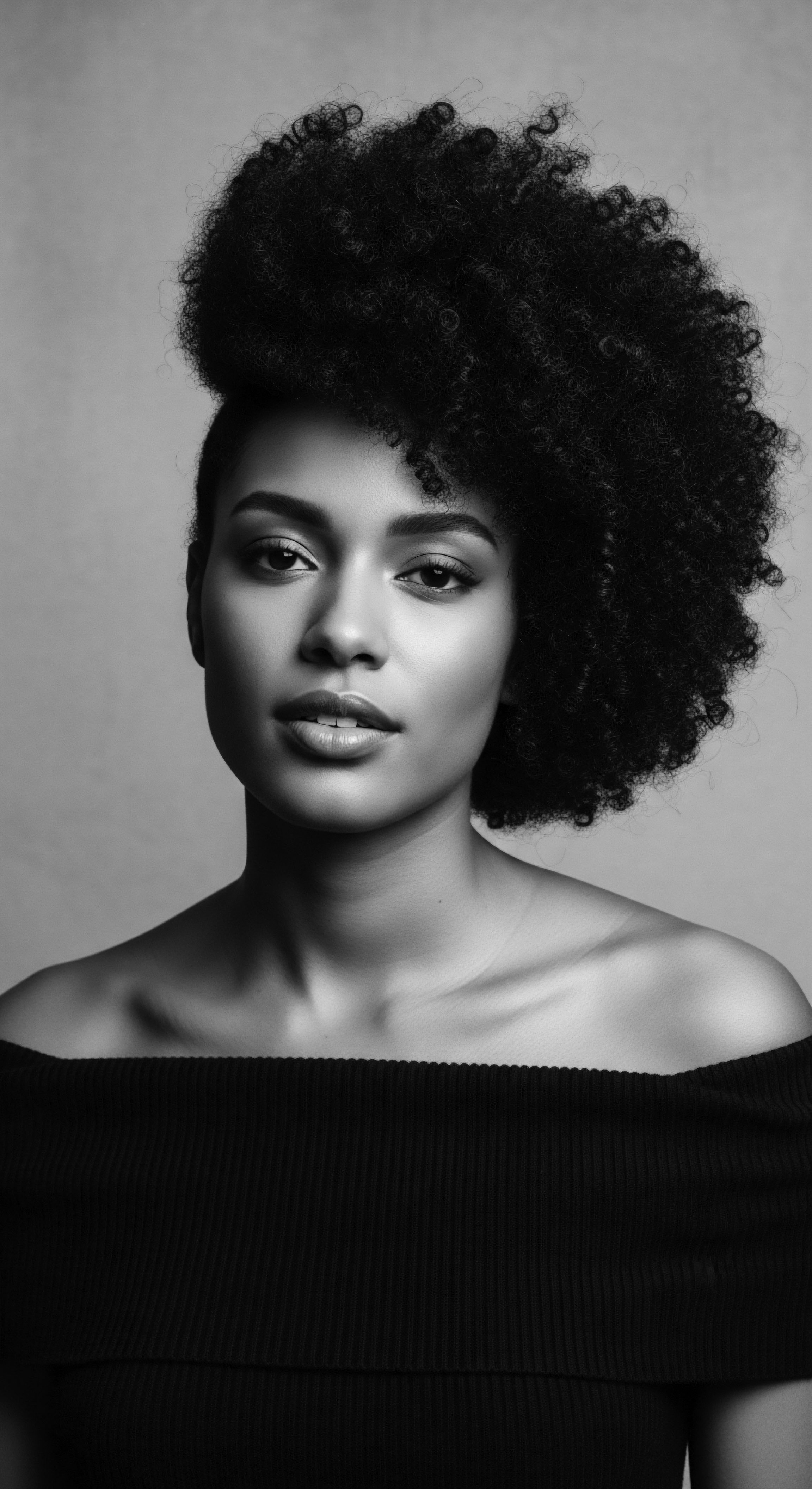 Striking Black and White Portrait Woman with Afro Textured Hair Style The black and white palette emphasizes the profound beauty of the woman’s texture and the intricate details of her Afro hair, symbolizing strength and cultural identity through expressive styling. This image captures a moment of timeless elegance, celebrating heritage and holistic hair care practices.