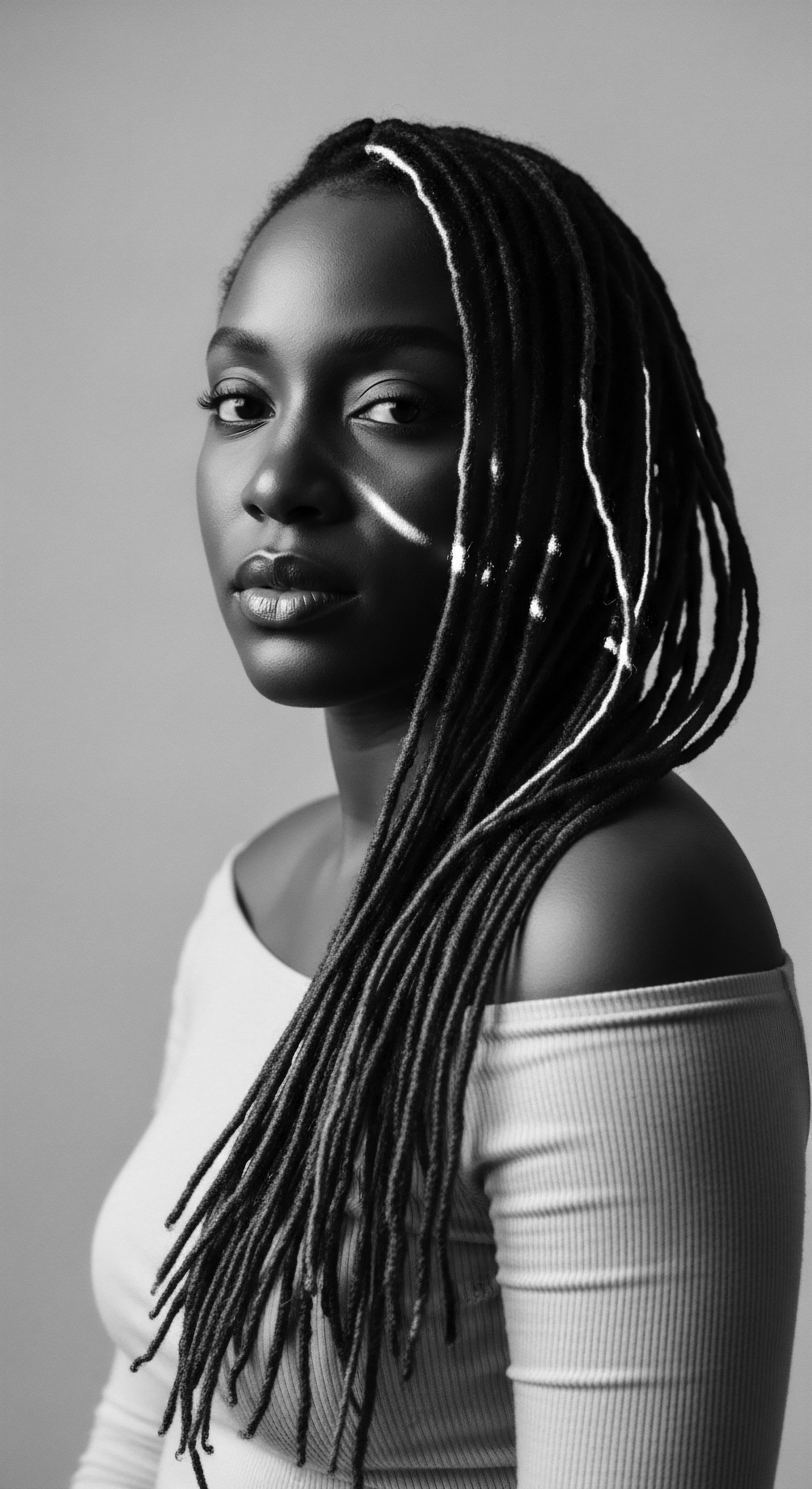 This monochrome image captures the beauty of black hair traditions embodied in protective styling. The contrast of light and shadow accentuates the texture of her locs, reflecting both strength and vulnerability. Textured hair in art elevates the interplay of identity, beauty, and ancestral connection.