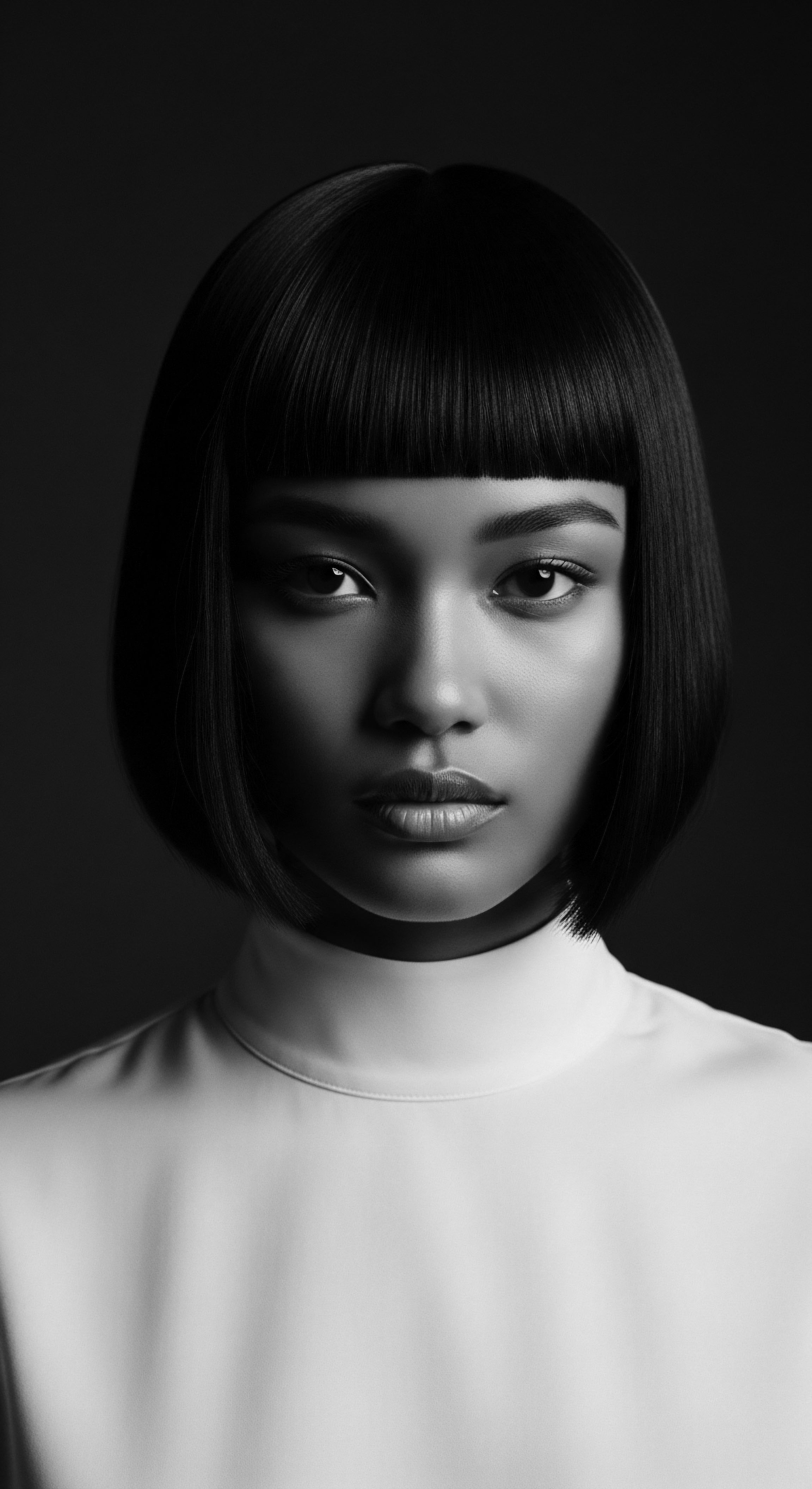 Striking Portrait of Asian Woman with Sleek Bob and Blunt Bangs The stark black and white enhances the woman's features and showcases the dramatic lines of the haircut, speaking to classic beauty standards while inviting reflection on the power and versatility of straight hair within diverse cultural expressions of style.