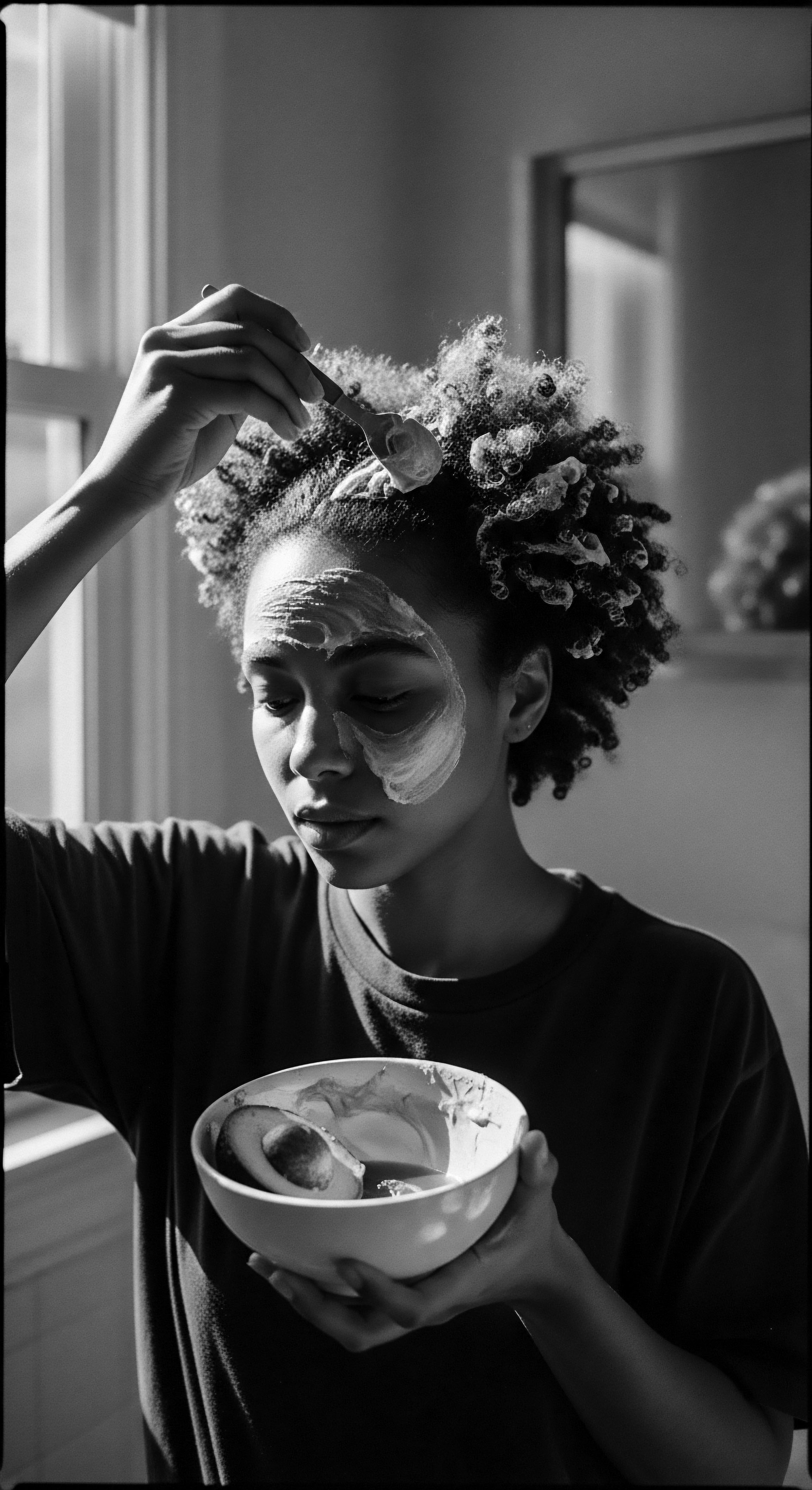 Woman Applies Natural Avocado Hair Mask for Textured Hair Wellness The application of an avocado mask embodies a holistic approach to textured hair health, celebrating ancestral practices and emphasizing the importance of moisture retention and scalp health for optimal coil definition and resilience, reflecting a commitment to natural wellness.