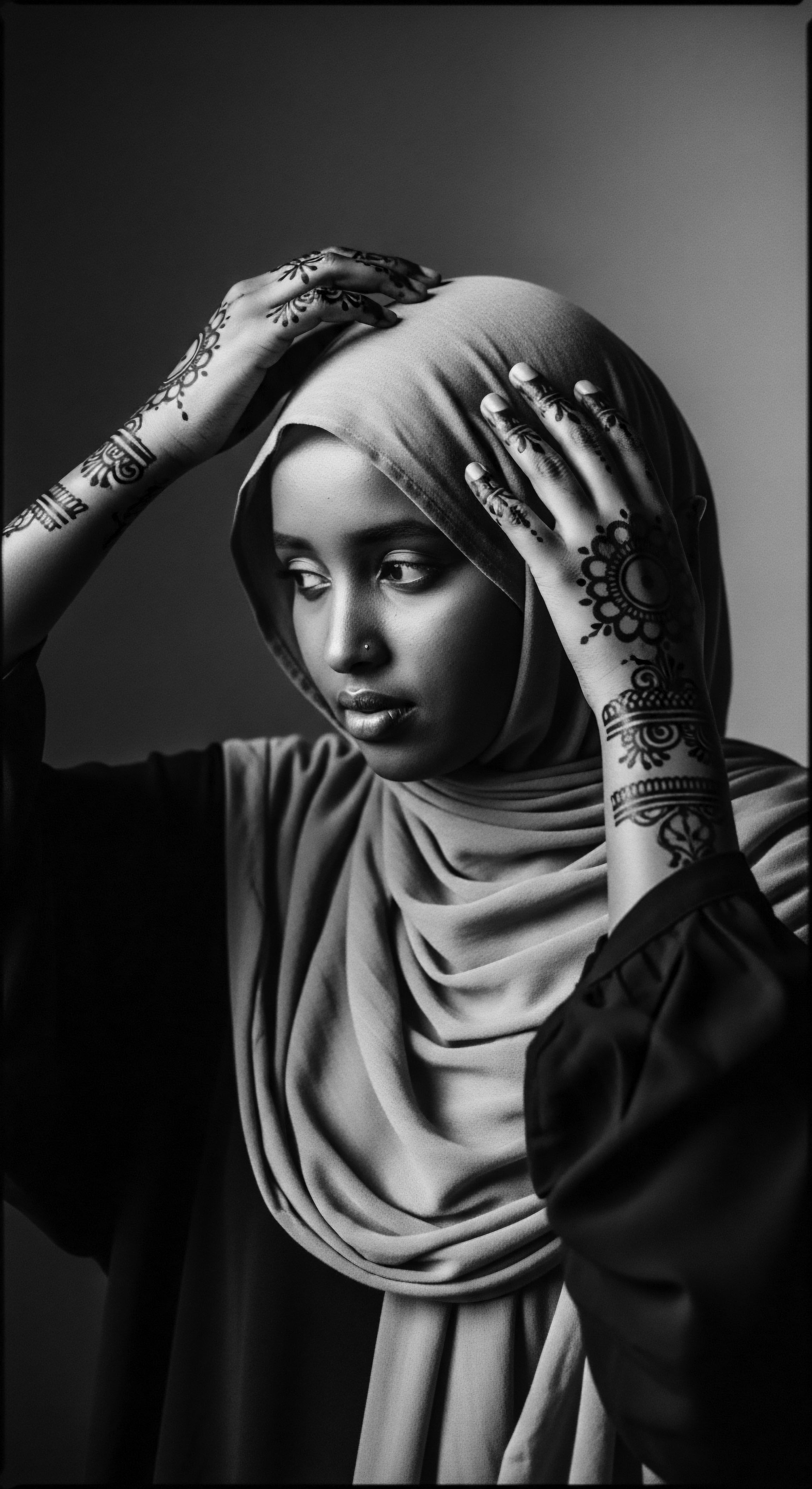 Woman in Hijab with Henna Design and Traditional Black Hair Updo The evocative black and white portrait captures the essence of cultural pride, blending henna artistry, a traditional hijab, and healthy low porosity high-density hair, symbolizing ancestral heritage and self-expression, resonating with a narrative of identity through art and spiritual wellness.