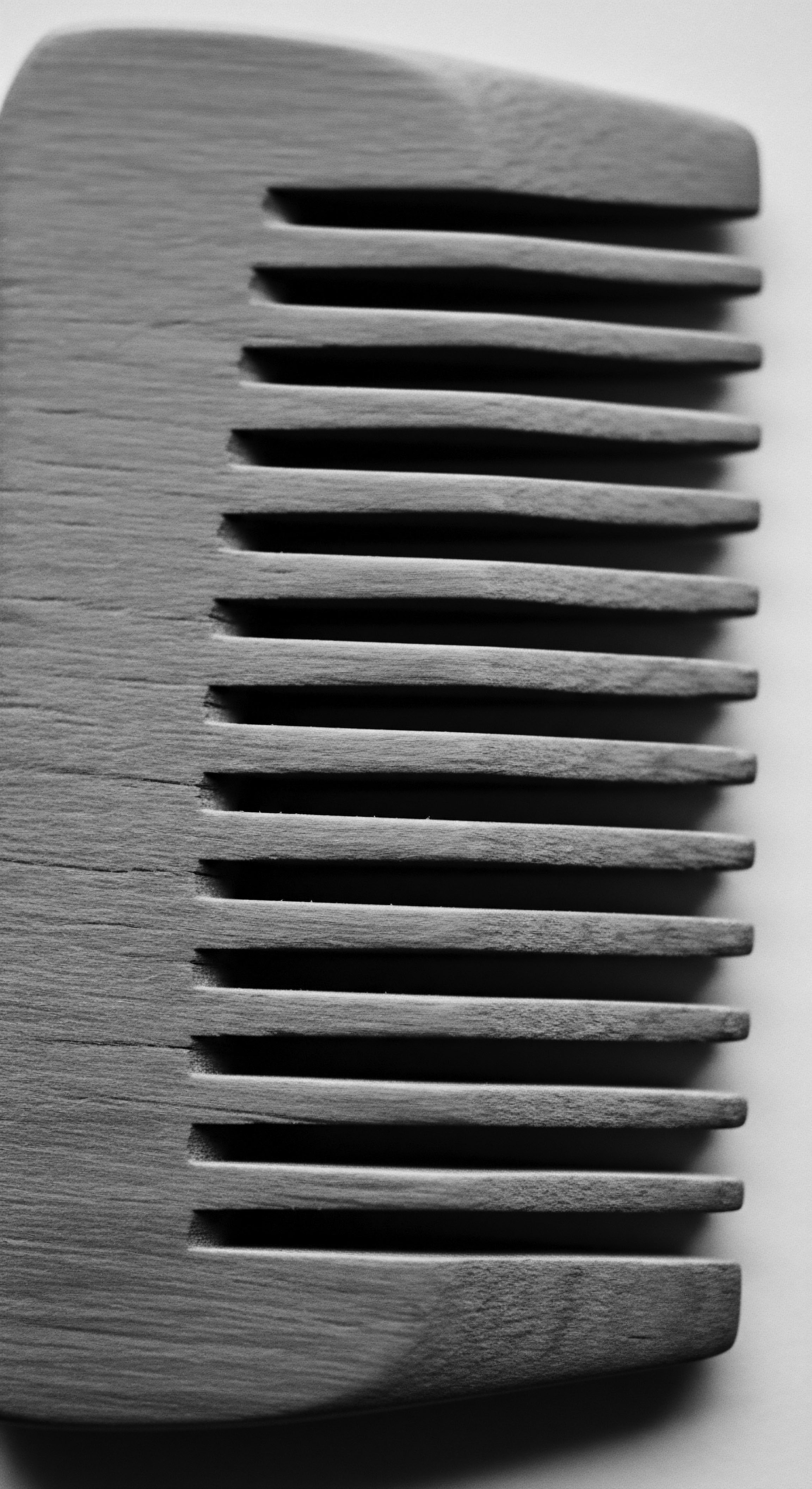 Wooden Comb Revealing Hair Texture Density Holistic Scalp Care Approach This wooden comb symbolizes mindful haircare, resonating with time-honored rituals that embrace the diverse array of textured hair patterns. Crafted for careful maintenance, it echoes traditions of holistic wellness, celebrating cultural roots and conscious beauty through ancestral practices of grooming.