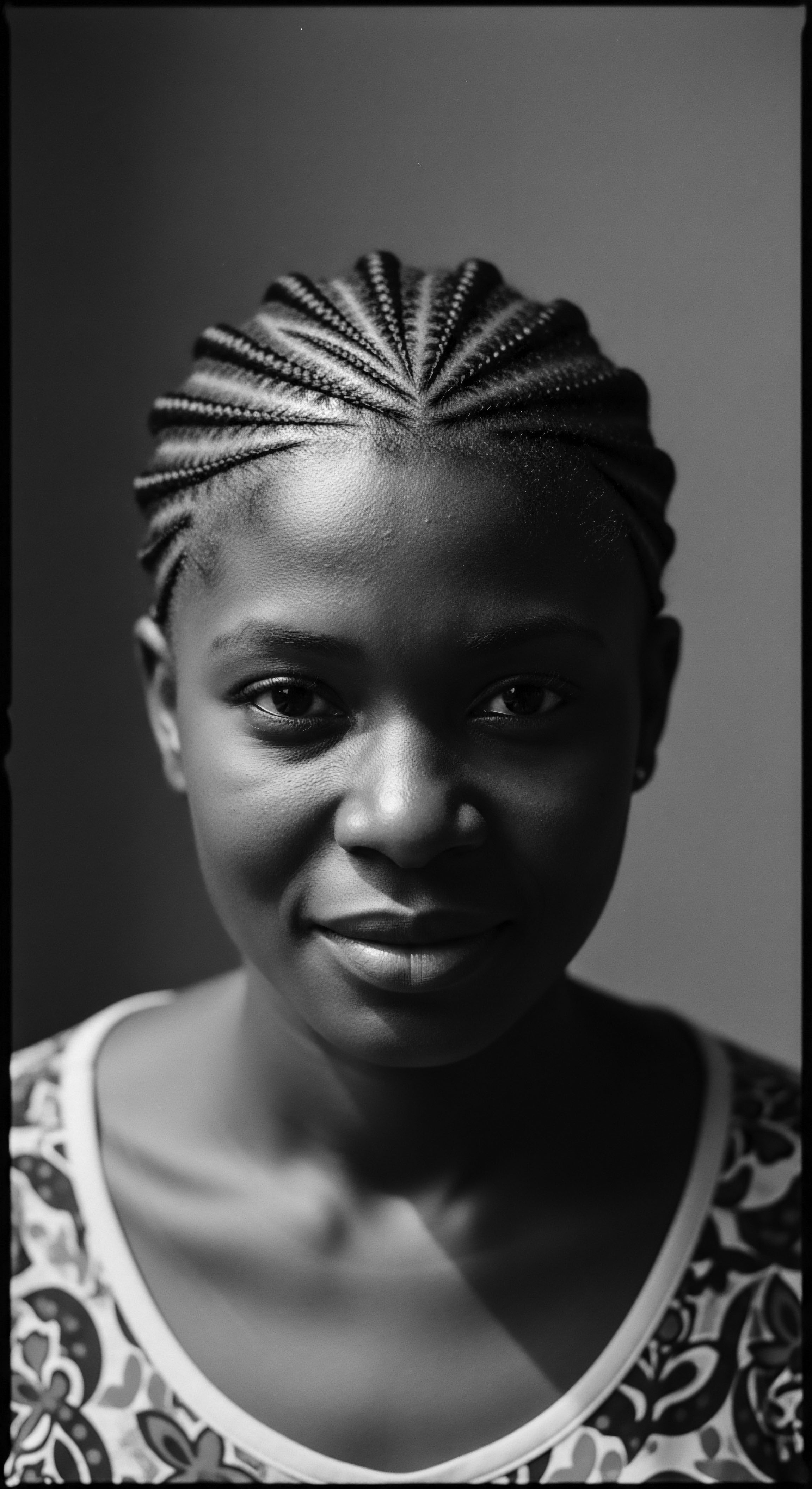 This portrait captures the essence of beauty through textured hair expression, showcasing cornrow braids as a celebration of ancestral heritage and a symbol of self-care. The geometric patterns create a striking visual narrative, reflecting cultural identity with depth and grace.